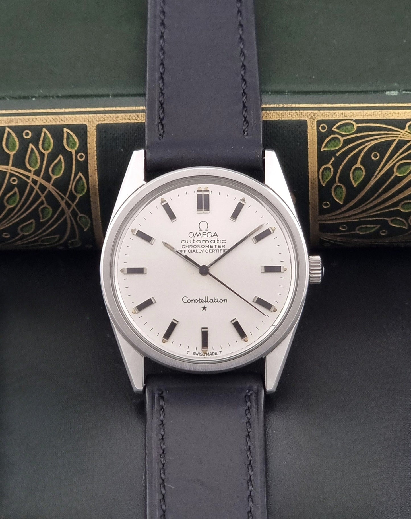 Vintage Omega Constellation 167.021 watch with a silver-toned case and black leather strap, on a dark background dial view