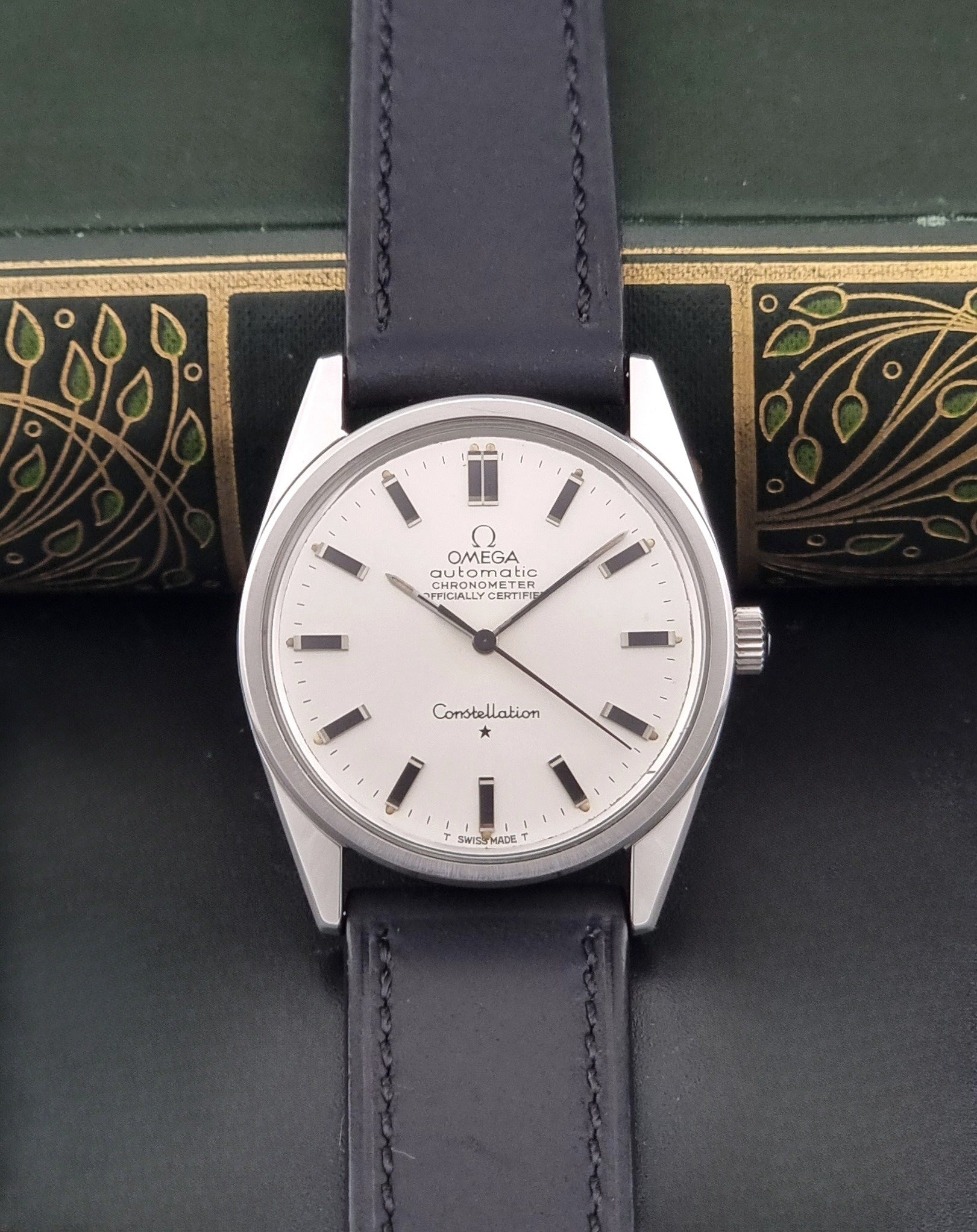 Vintage Omega Constellation 167.021 watch with a silver-toned case and black leather strap, on a dark background dial view