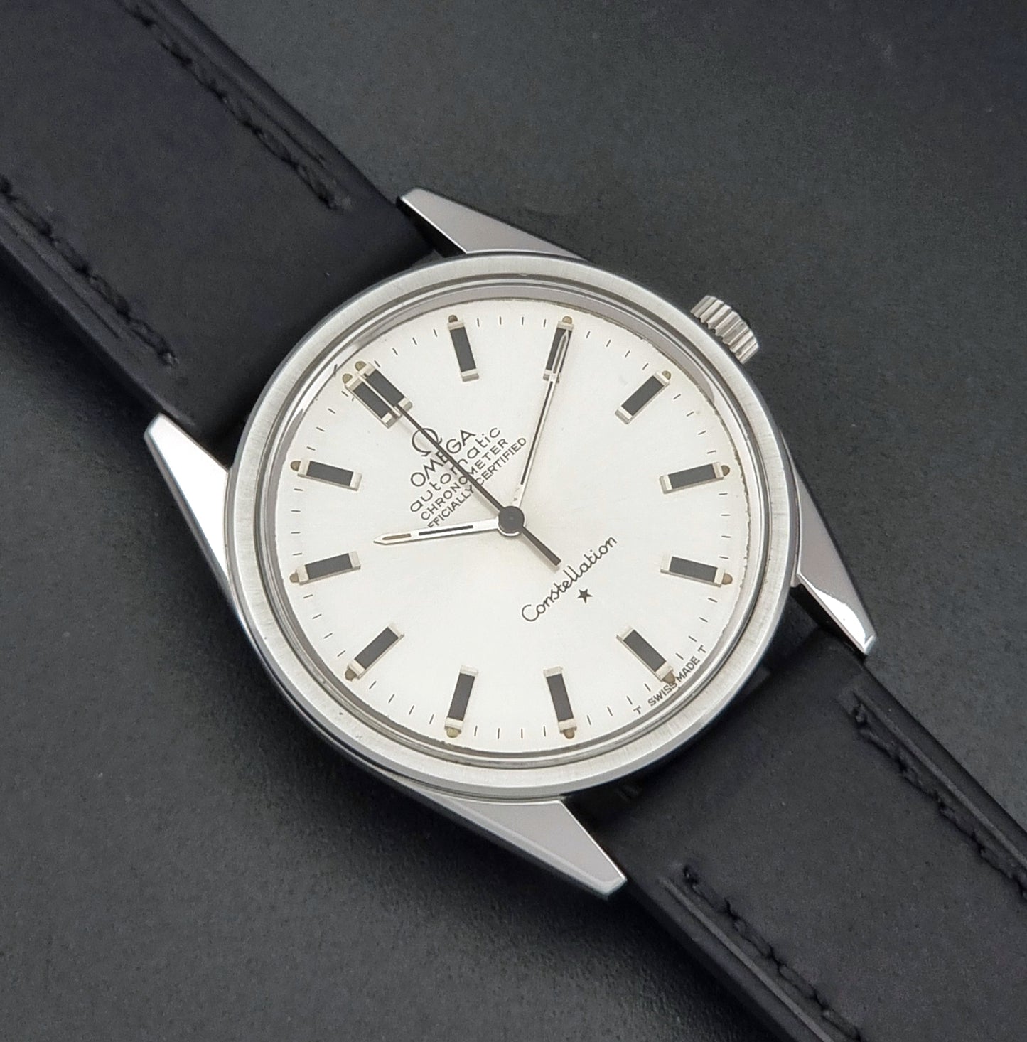 Vintage Omega Constellation 167.021 watch with a silver-toned case and black leather strap, on a dark background close up dial view