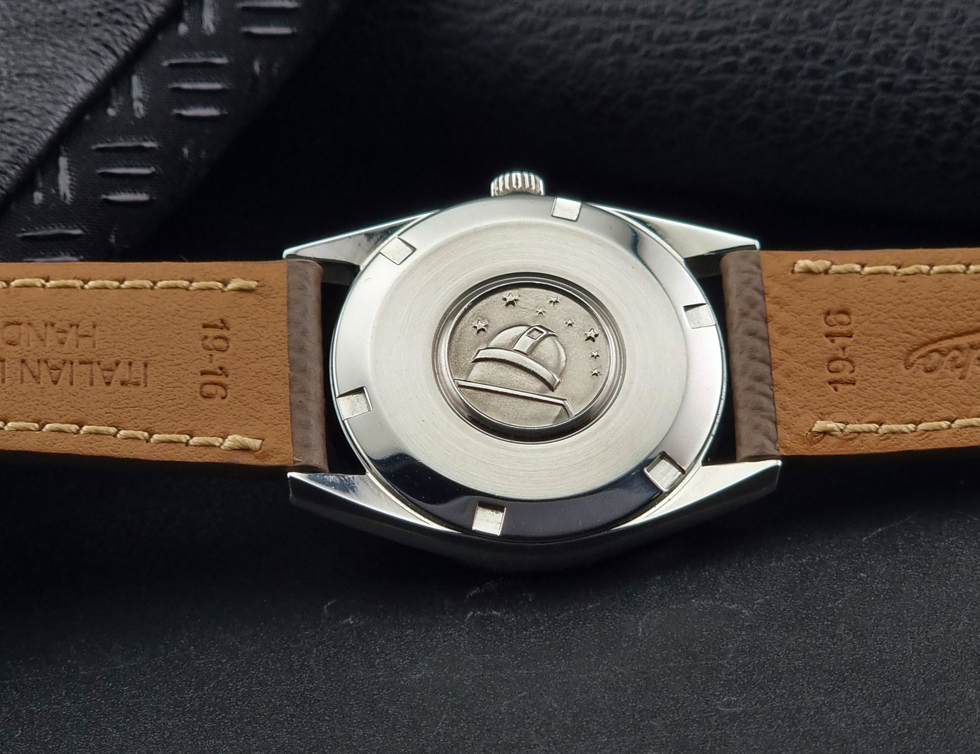 Vintage Omega watch Constellation 167.021 Chronometer with brown leather strap on a dark gray background case back view