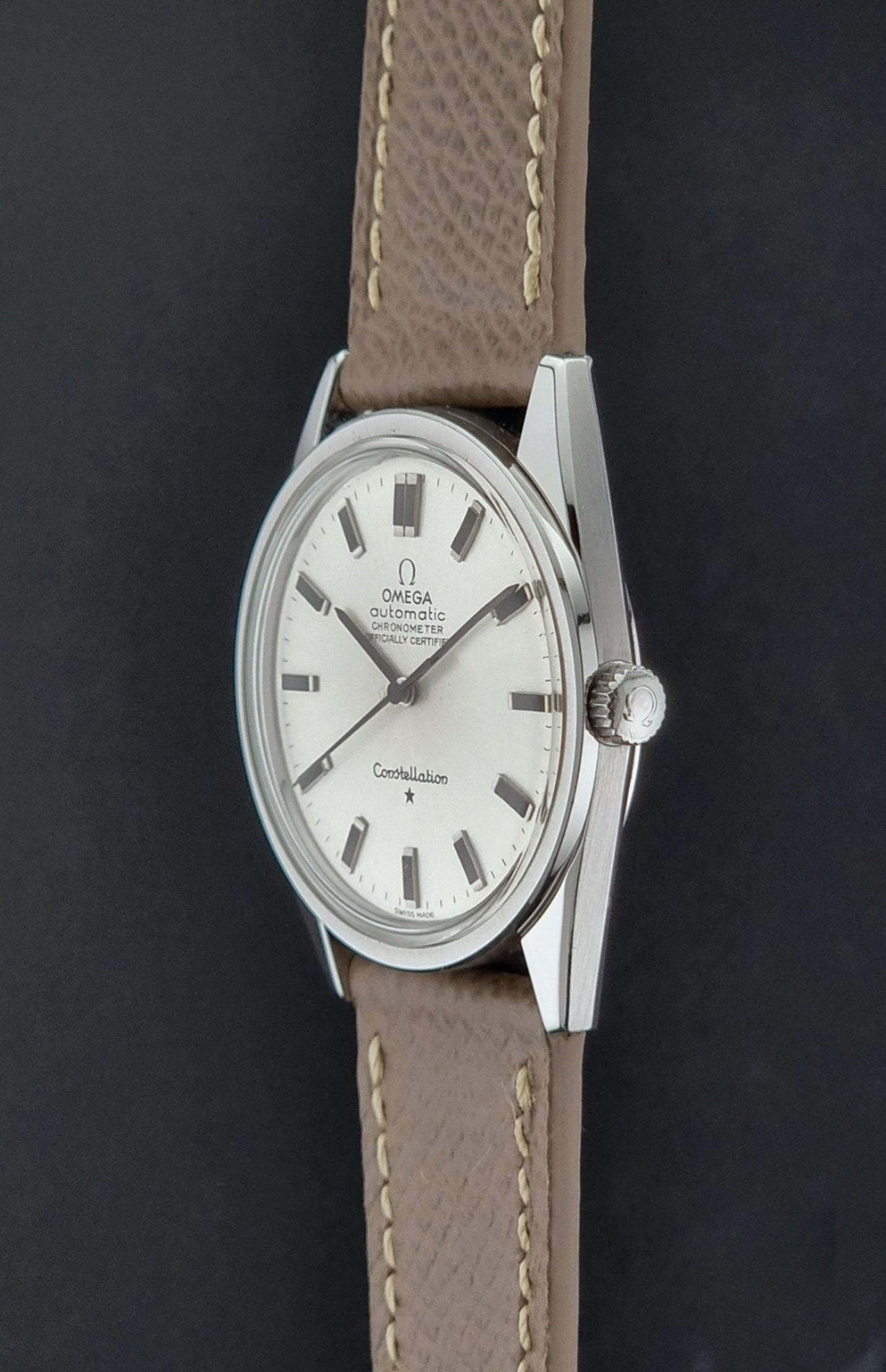 Vintage Omega watch Constellation 167.021 Chronometer with brown leather strap on a dark gray background crown profile view