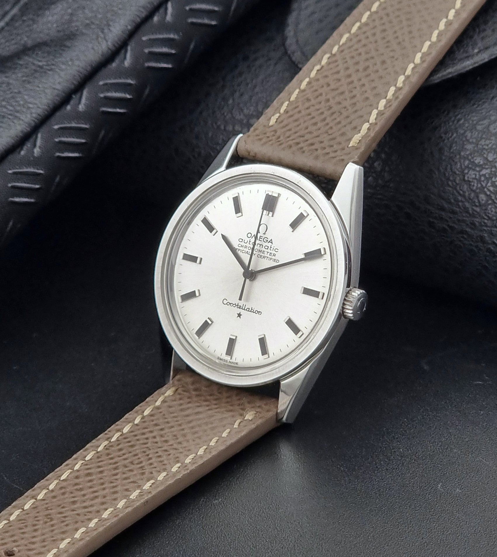 Vintage Omega watch Constellation 167.021 Chronometer with brown leather strap on a dark gray background crown view