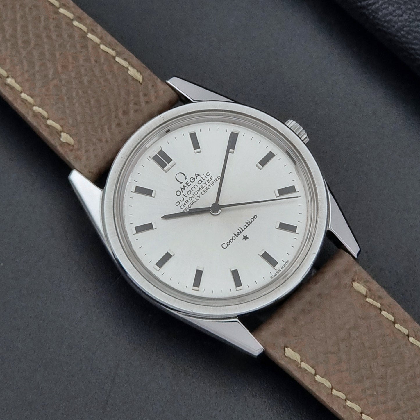 Vintage Omega watch Constellation 167.021 Chronometer with brown leather strap on a dark gray background close up dial view