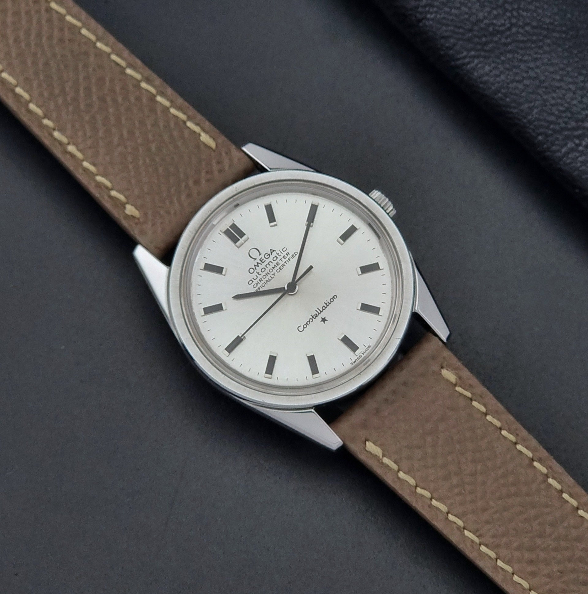 Vintage Omega watch Constellation 167.021 Chronometer with brown leather strap on a dark gray background dial