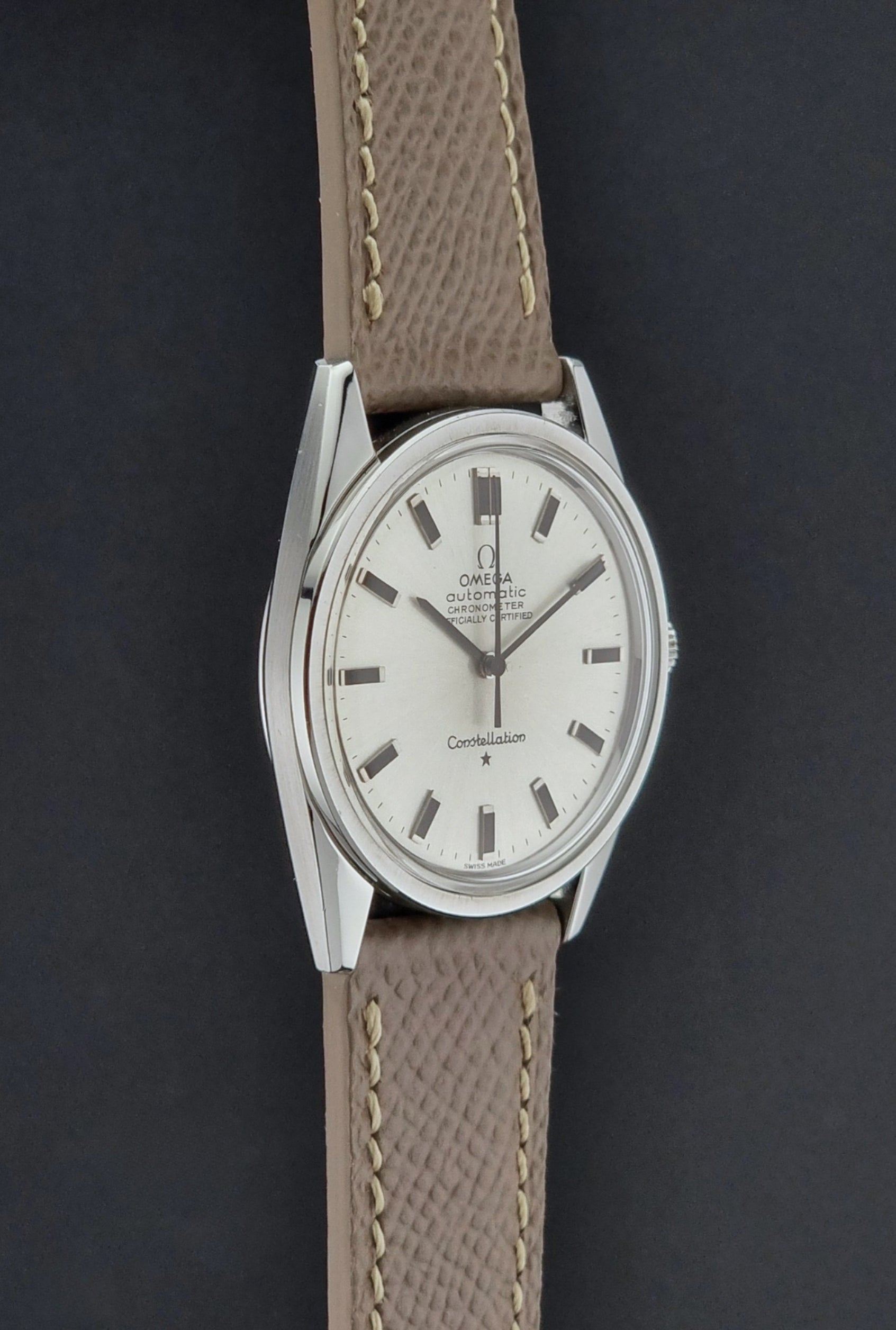 Vintage Omega watch Constellation 167.021 Chronometer with brown leather strap on a dark gray background side profile view