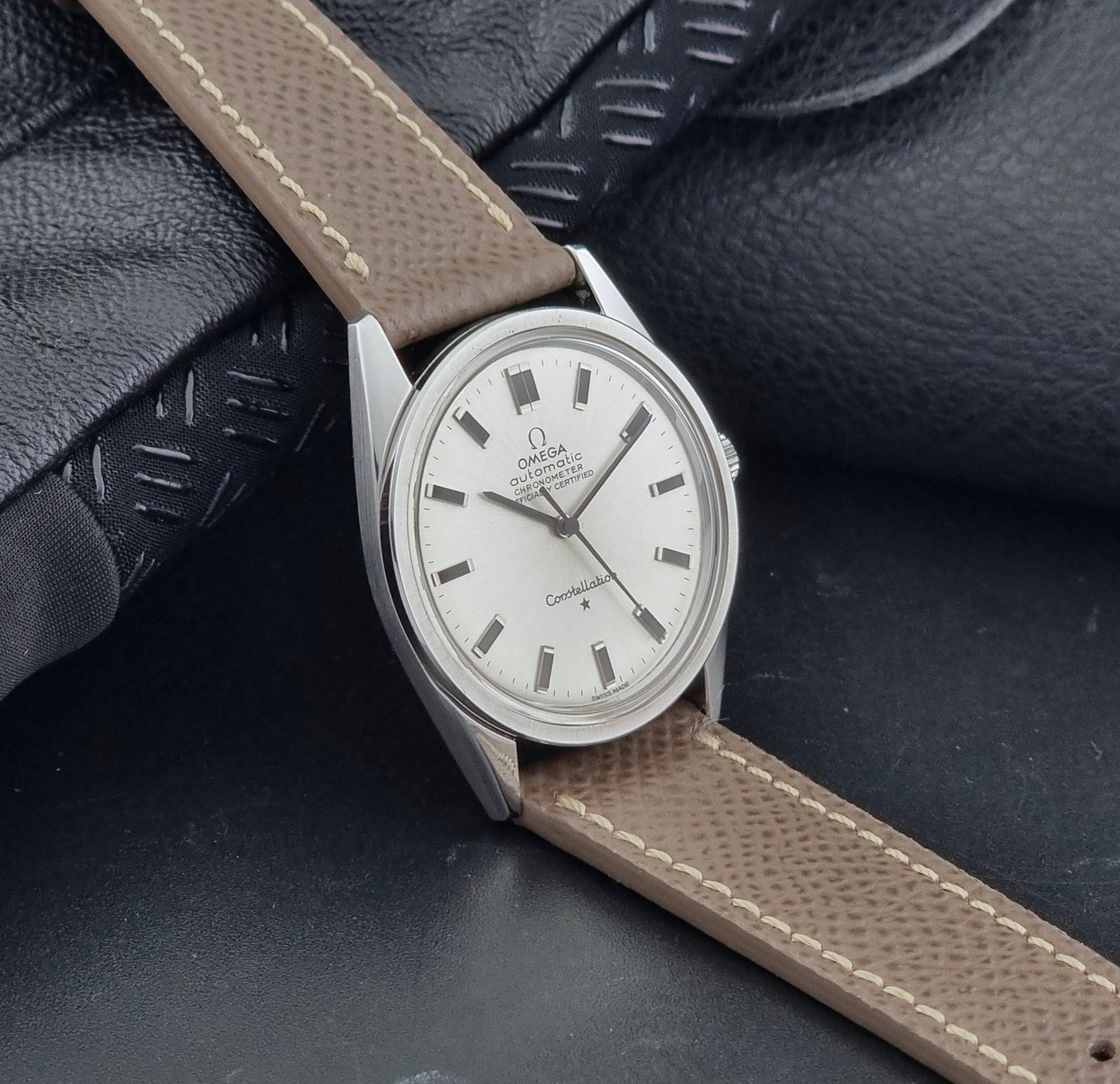 Vintage Omega watch Constellation 167.021 Chronometer with brown leather strap on a dark gray background side view