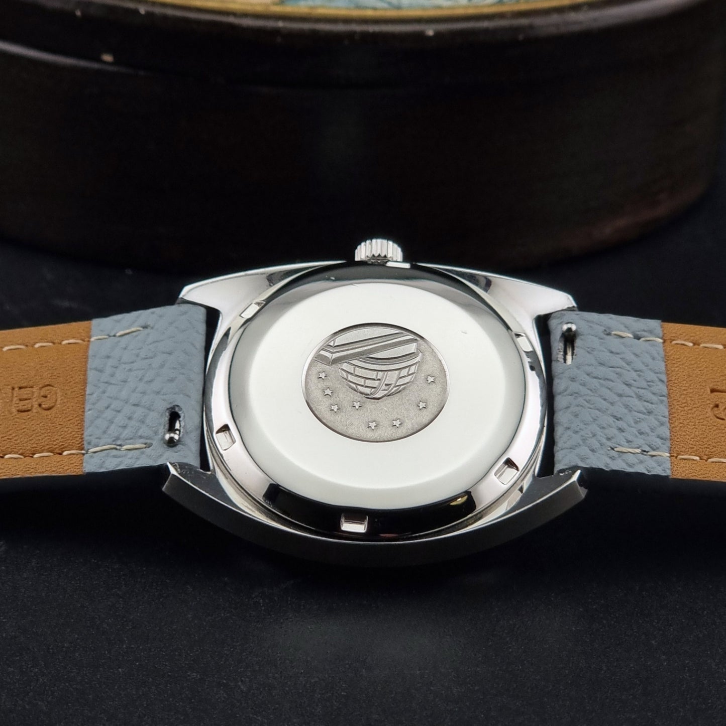 Vintage Omega Constellation 168.017 with a grey leather strap on a dark background case back view