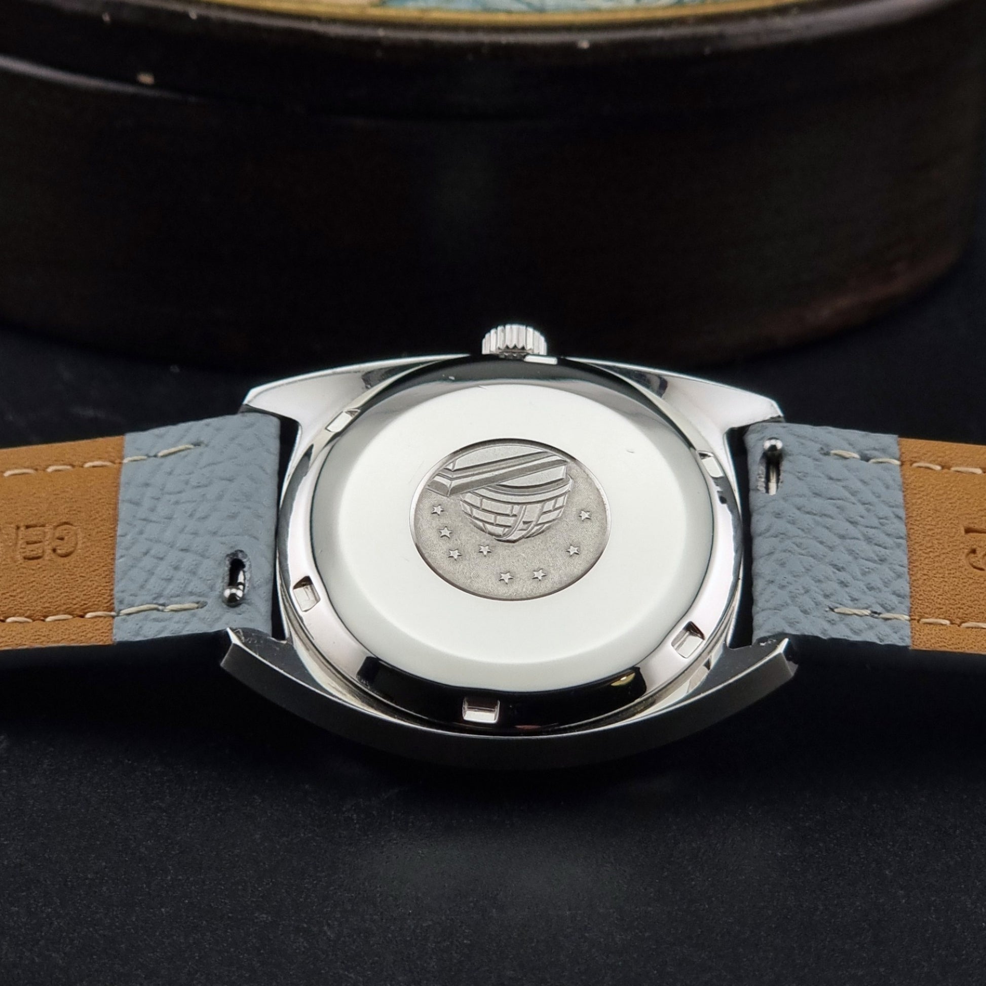 Vintage Omega Constellation 168.017 with a grey leather strap on a dark background case back view