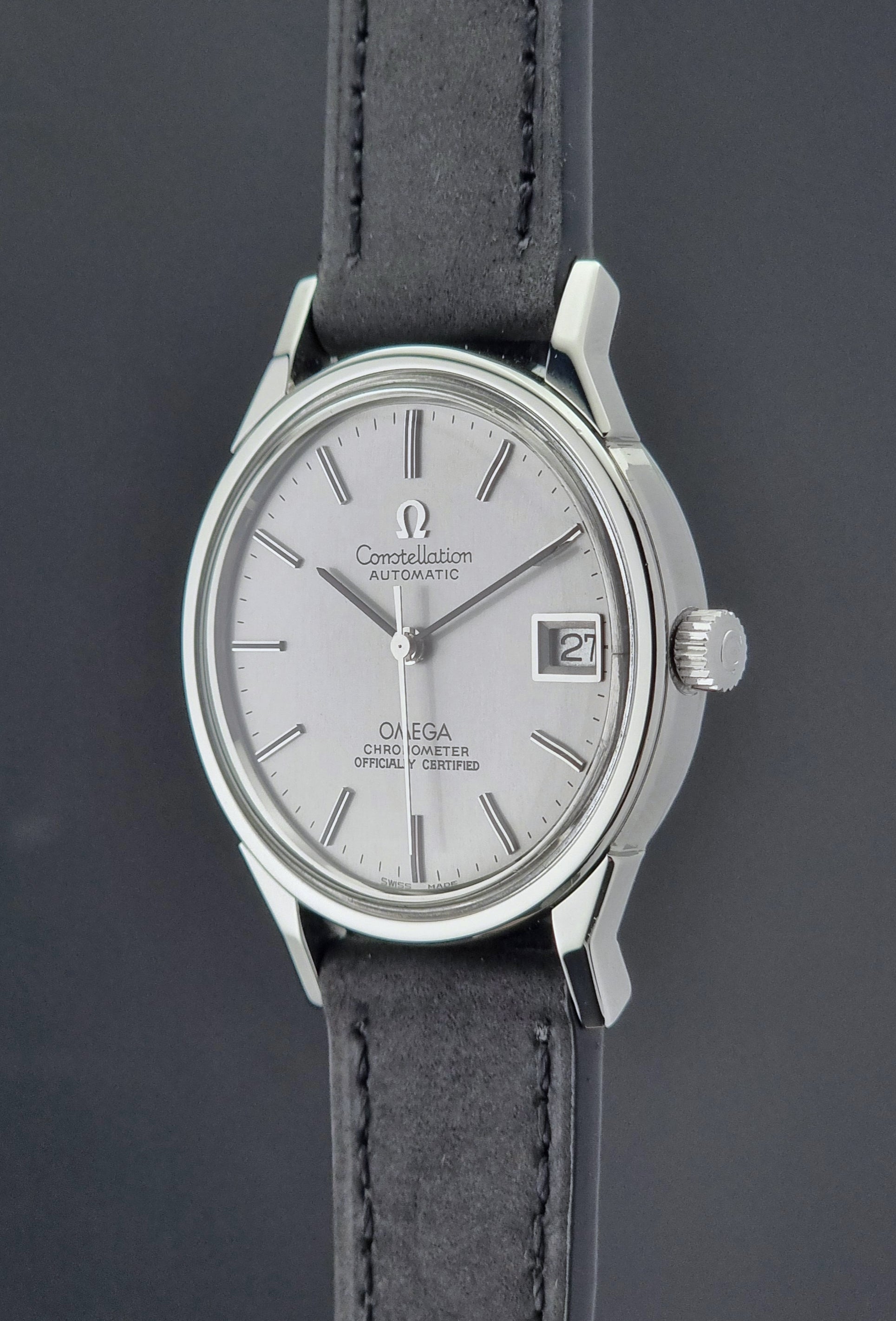 Omega watch with silver case and black leather strap on a dark background