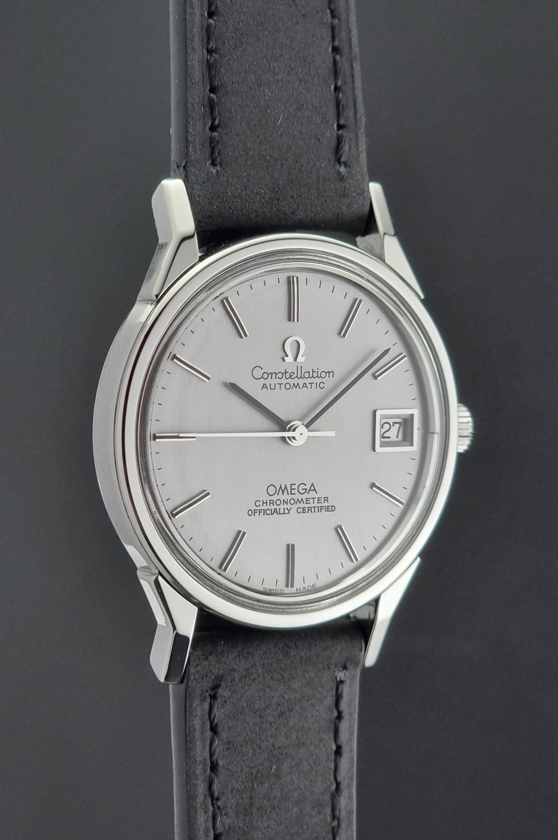 Omega watch with silver dial and black leather strap on a dark background
