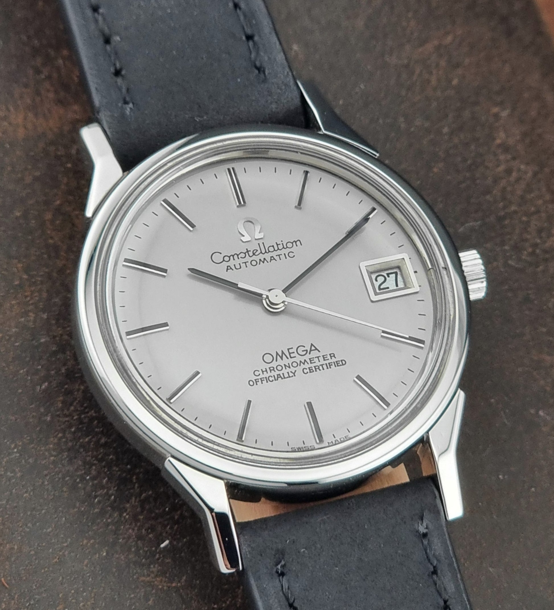 Omega Constellation watch with silver dial and black leather strap on a dark background