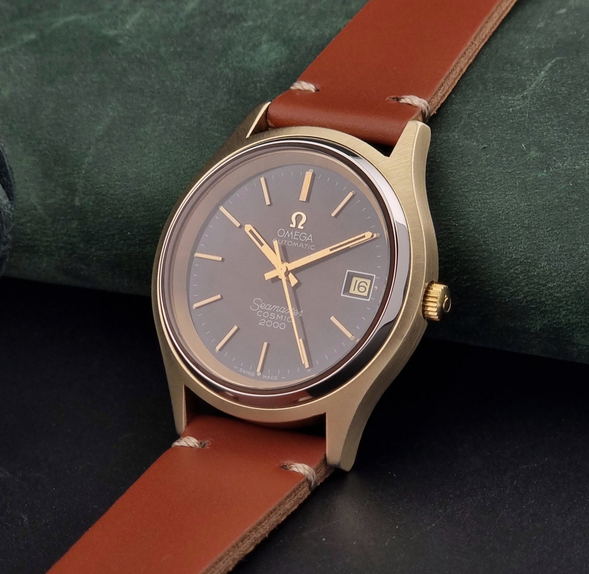 Vintage Omega Seamaster Cosmic 2000 watch with brown leather strap on a dark green background