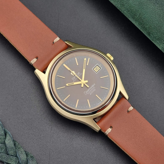 Vintage Omega Seamaster Cosmic 2000 Watch with brown leather strap and gold case on a dark gray background