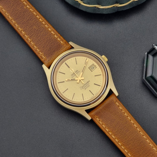 Vintage Omega Wristwatch Seamaster Cosmic 2000 Jumbo 166.128 in Gold with brown leather strap on a dark gray background dail