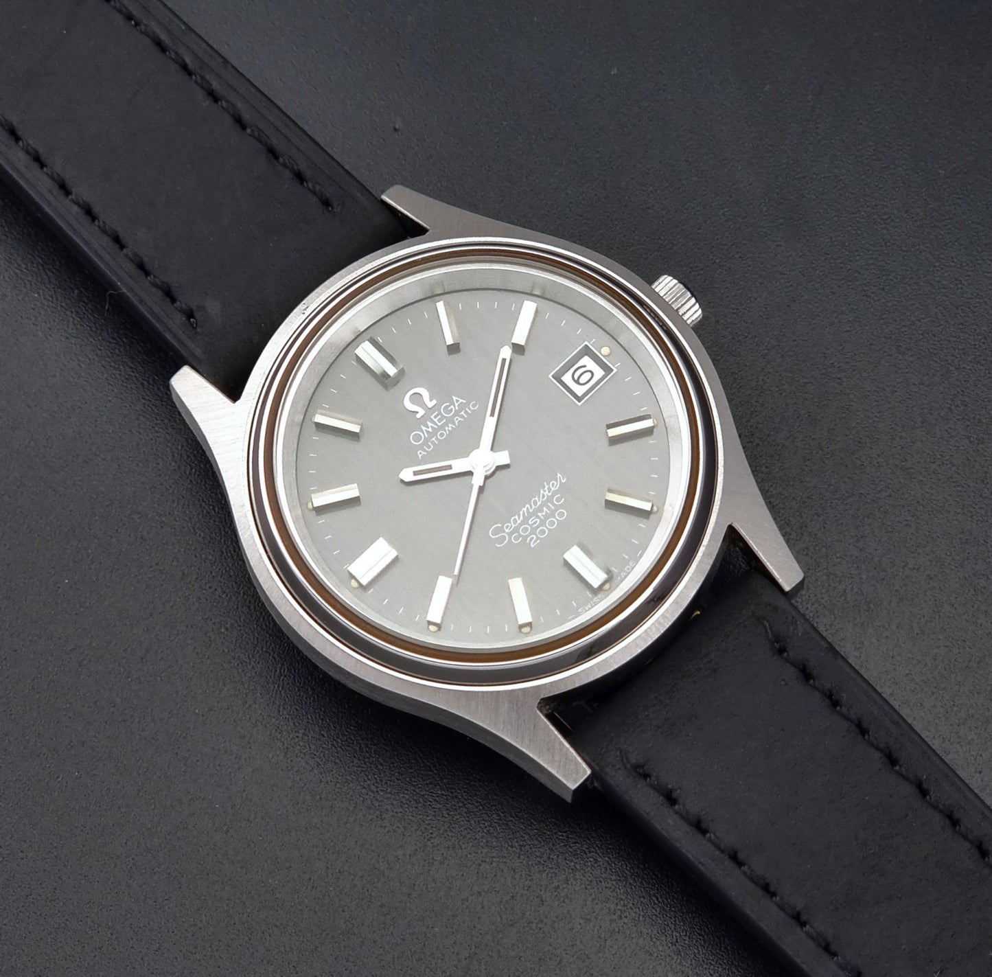 Vintage Omega Wristwatch Seamaster Cosmic 2000 Jumbo 166.128 grey dial with black leather strap on a dark gray background close up dial view