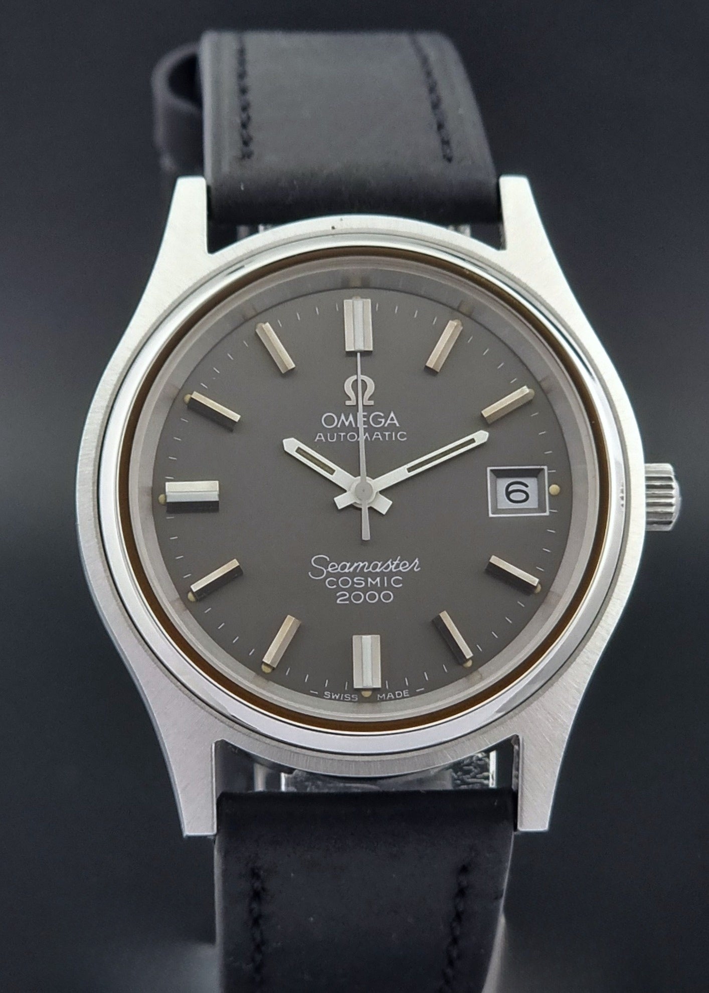 Vintage Omega Wristwatch Seamaster Cosmic 2000 Jumbo 166.128 grey dial with black leather strap on a dark gray background front view