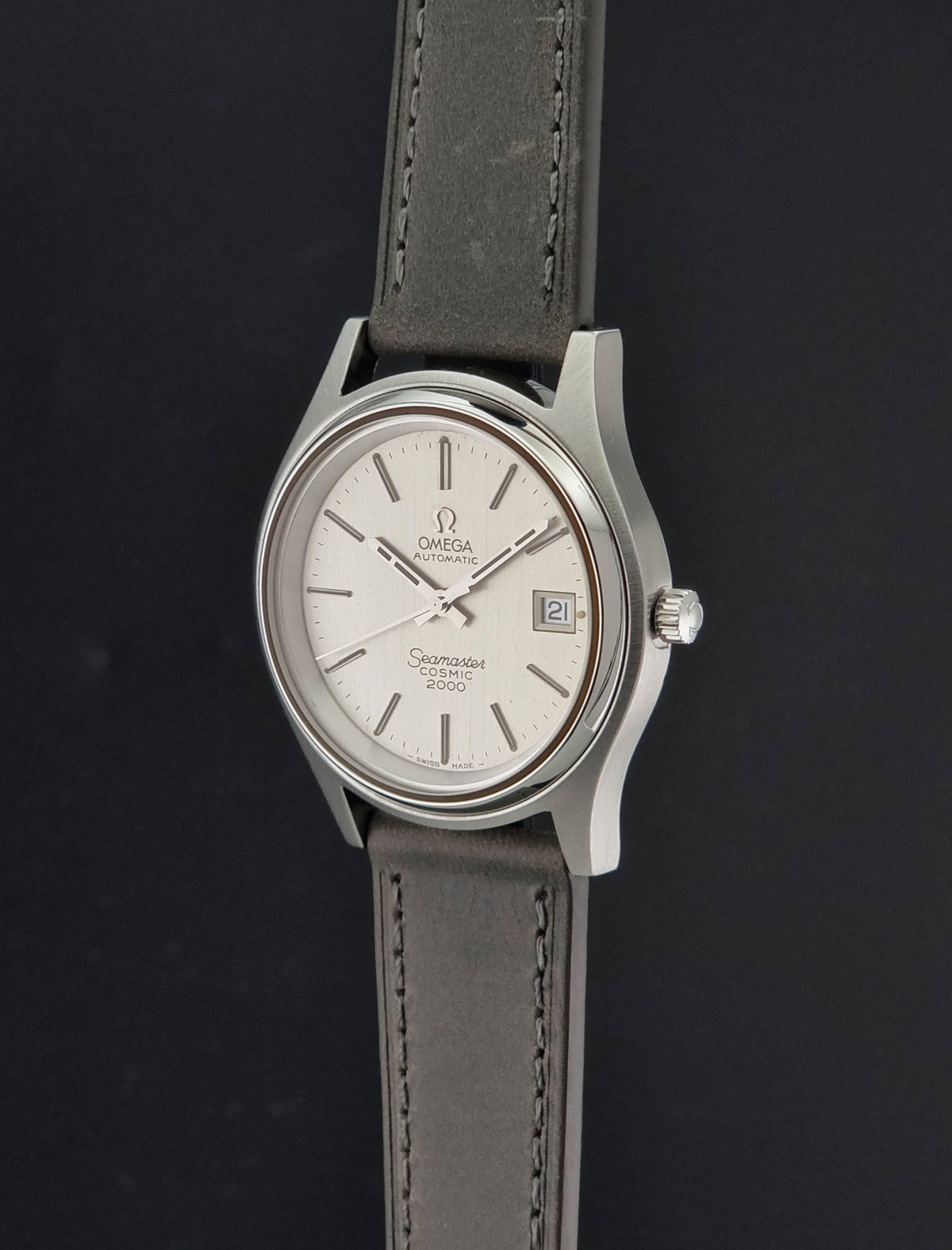 Vintage Omega Wristwatch 166.128 Seamaster Cosmic 2000 with a cream dial and stainless steel case suspended on a dark background
