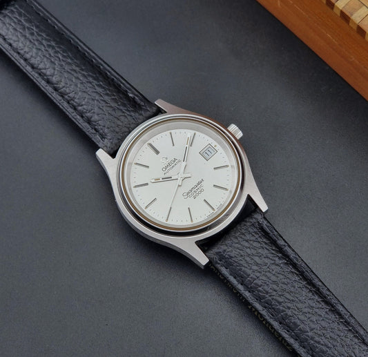 Vintage Omega Wristwatch 166.128 Seamaster Cosmic 2000 with black leather strap and silver case on a dark surface dial