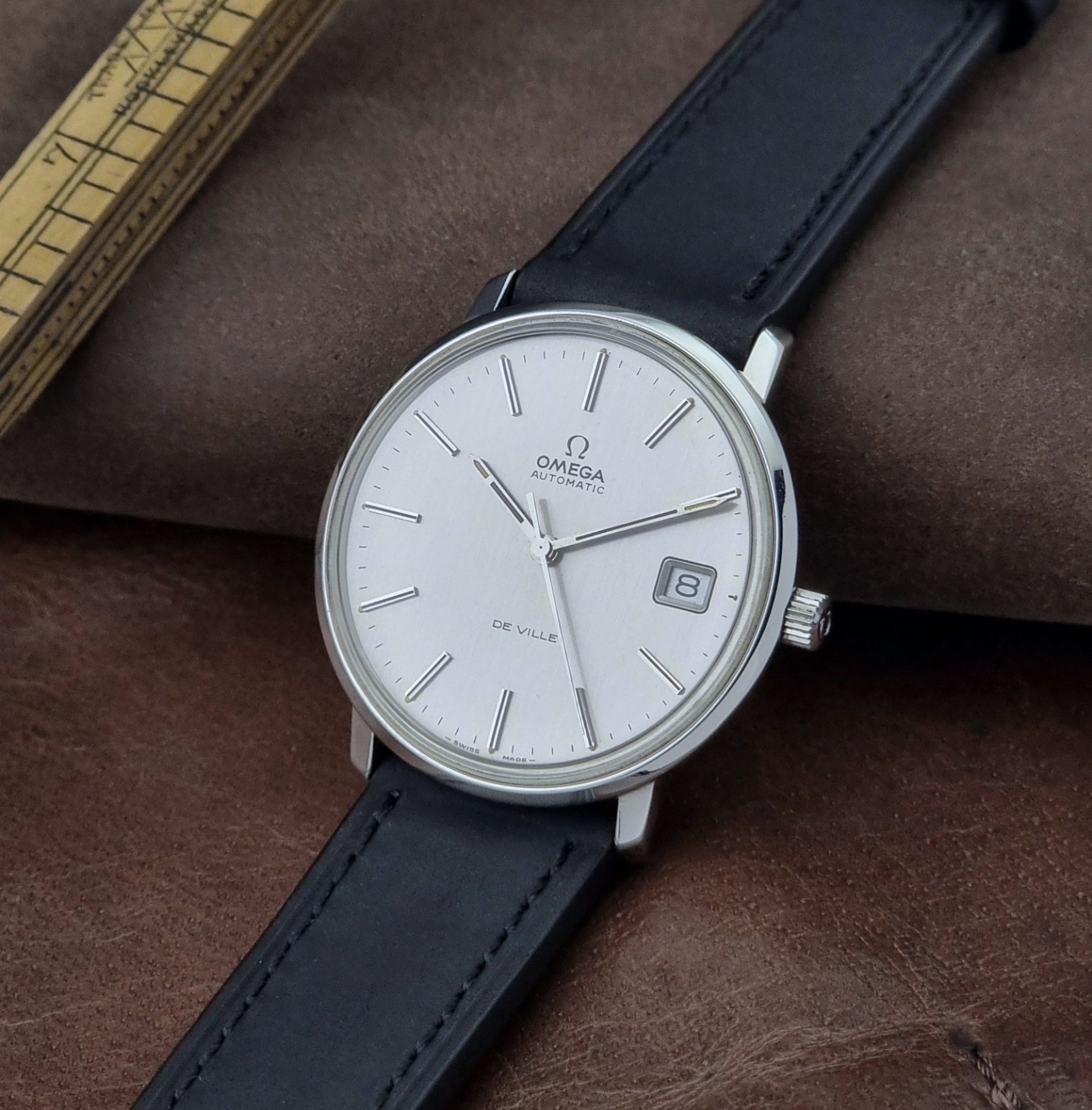 Vintage Omega de-ville wristwatch on a brown background crown view