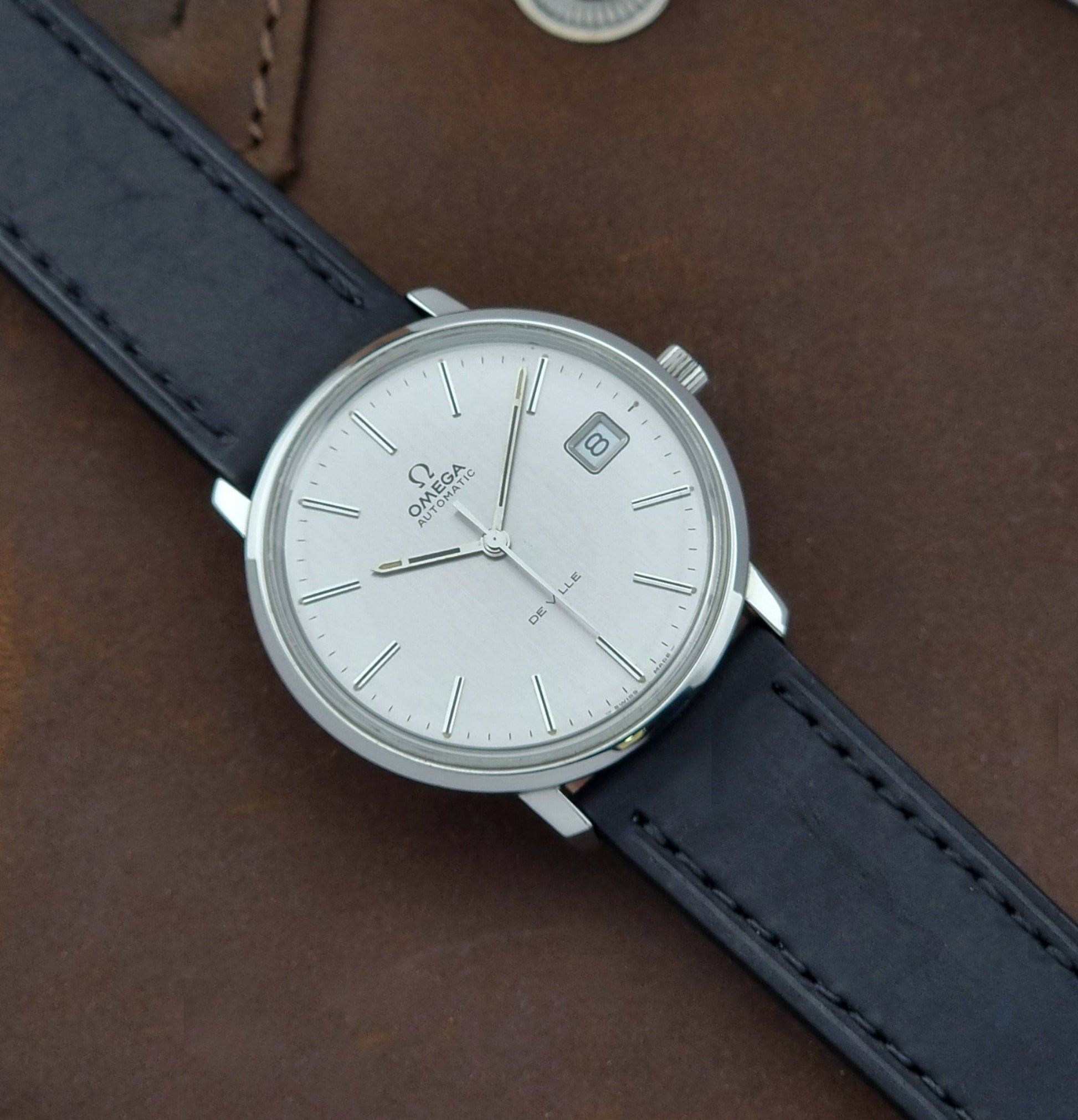 Vintage Omega de-ville wristwatch on a brown background front view