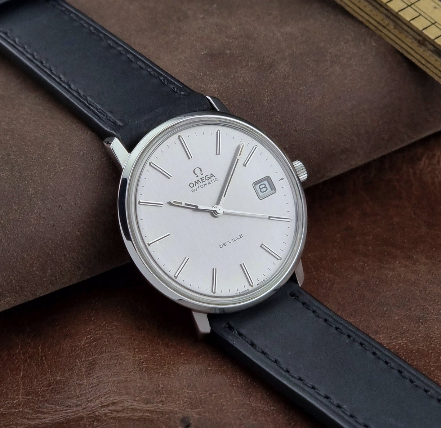 Vintage Omega de-ville wristwatch on a brown background side view