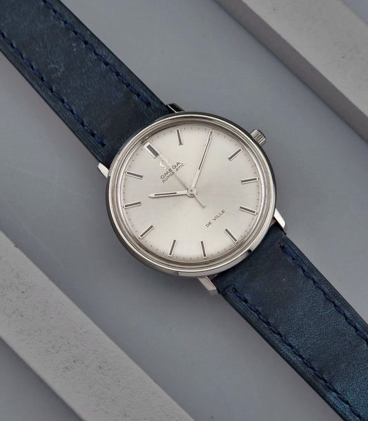 Vintage Omega De-Ville watch with blue leather strap on a gray background