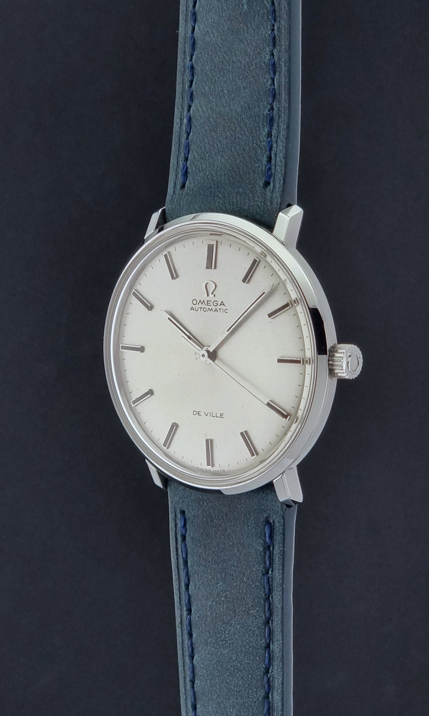 Vintage Omega Wristwatch De-Ville 165.033 with blue strap on a dark background crown profile view