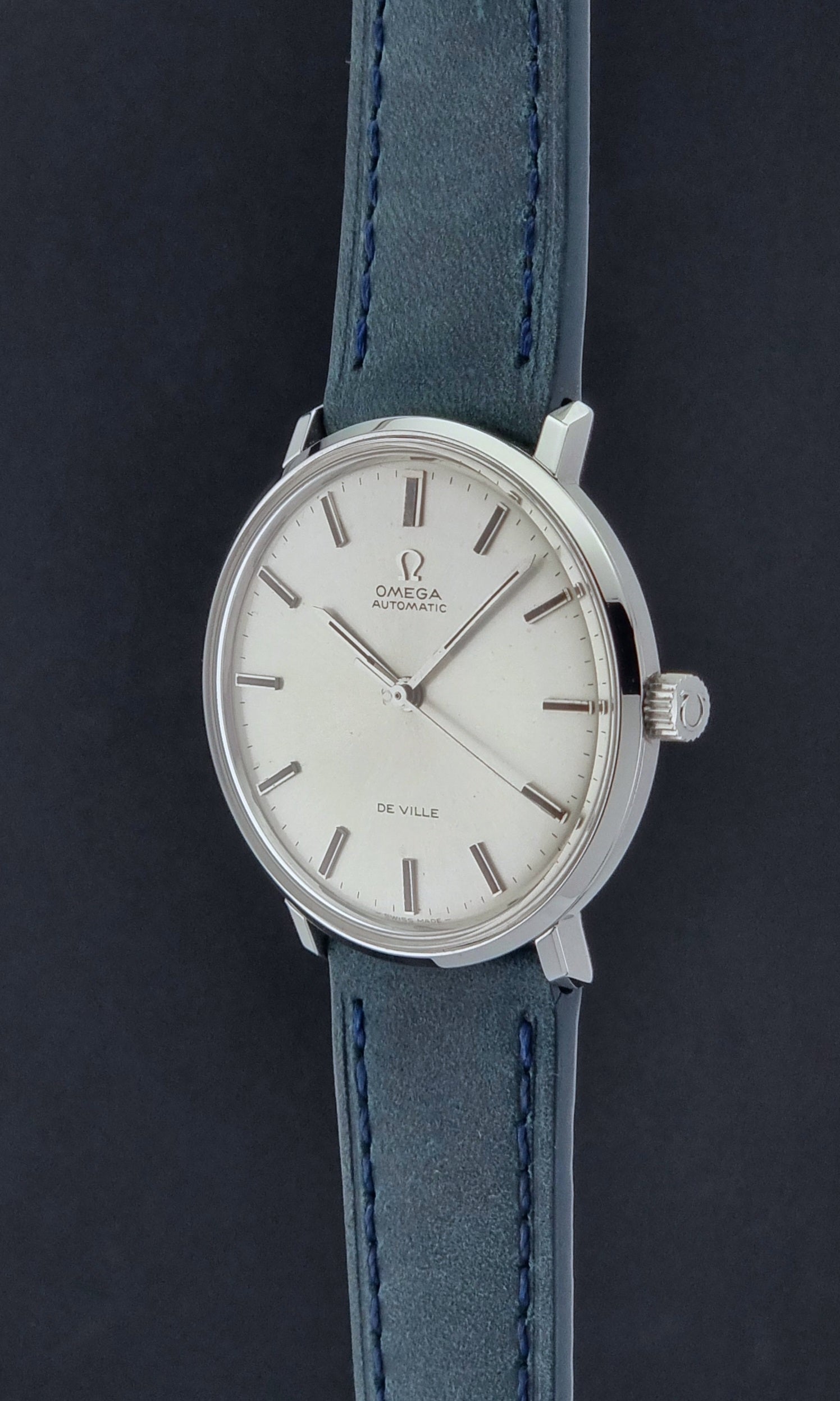 Vintage Omega Wristwatch De-Ville 165.033 with blue strap on a dark background crown profile view