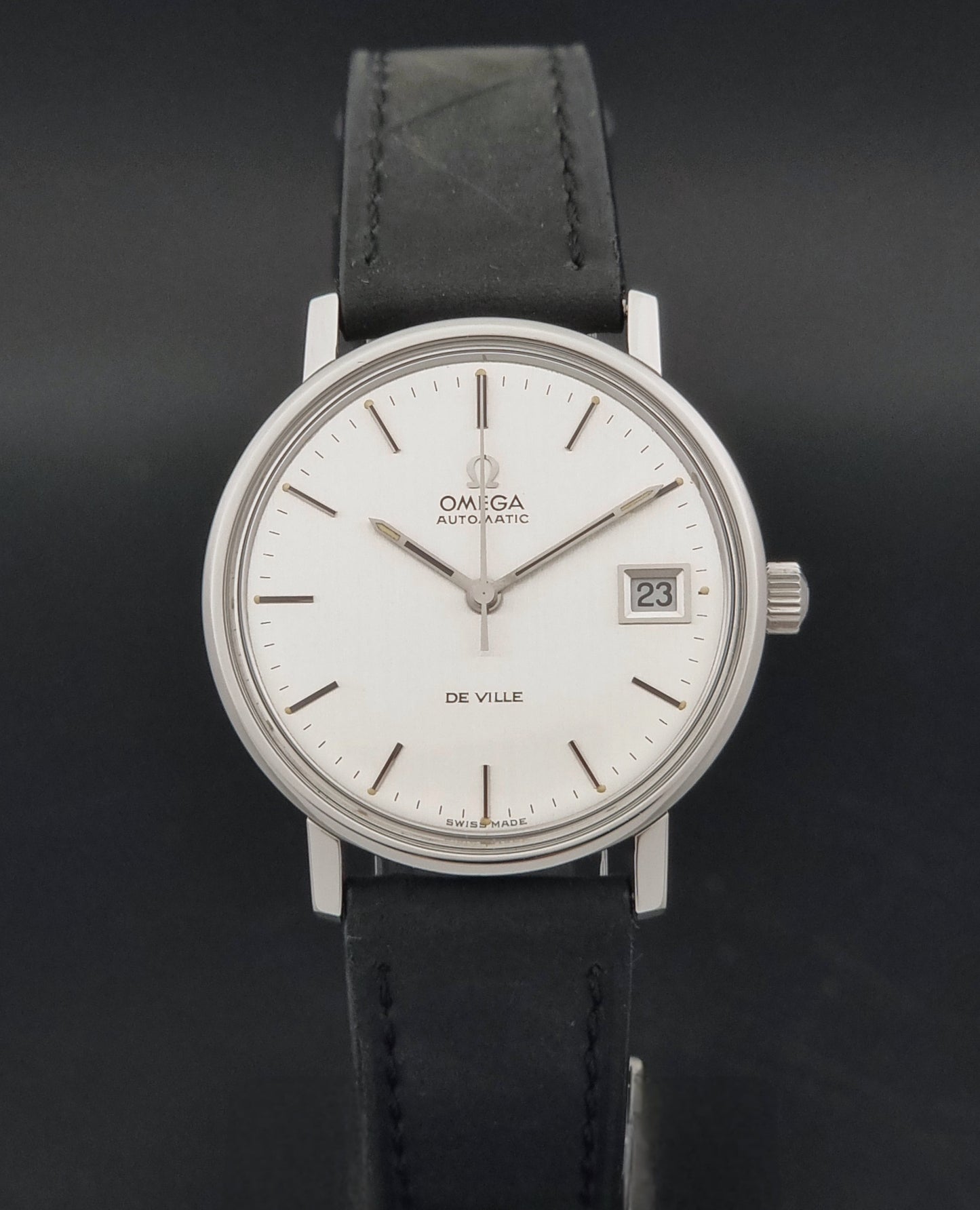Vintage Omega  De-Ville 166.0086 wristwatch with a silver-toned case, and black leather strap, photographed on a dark background close dial view
