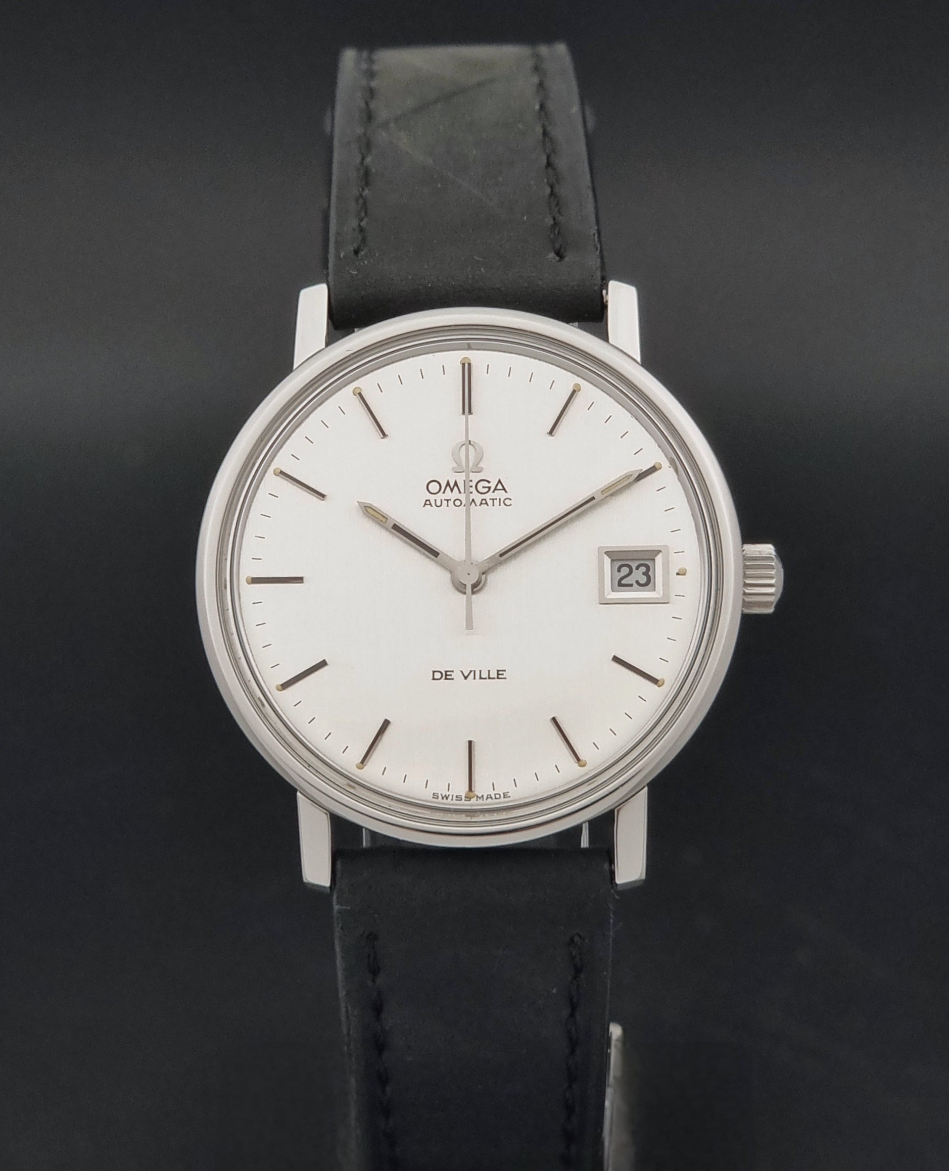 Vintage Omega  De-Ville 166.0086 wristwatch with a silver-toned case, and black leather strap, photographed on a dark background close dial view