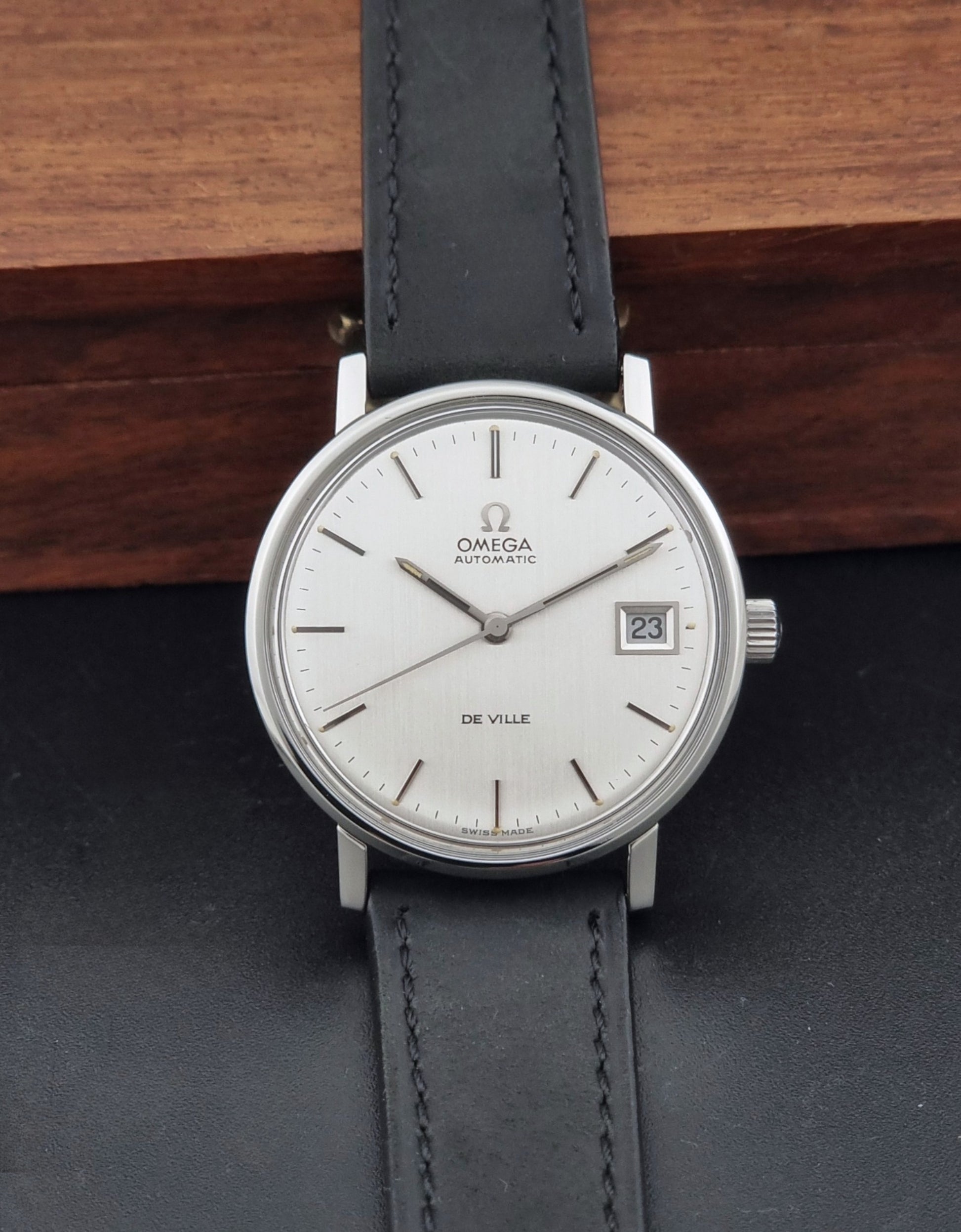 Vintage Omega  De-Ville 166.0086 wristwatch with a silver-toned case, and black leather strap, photographed on a dark background dial view