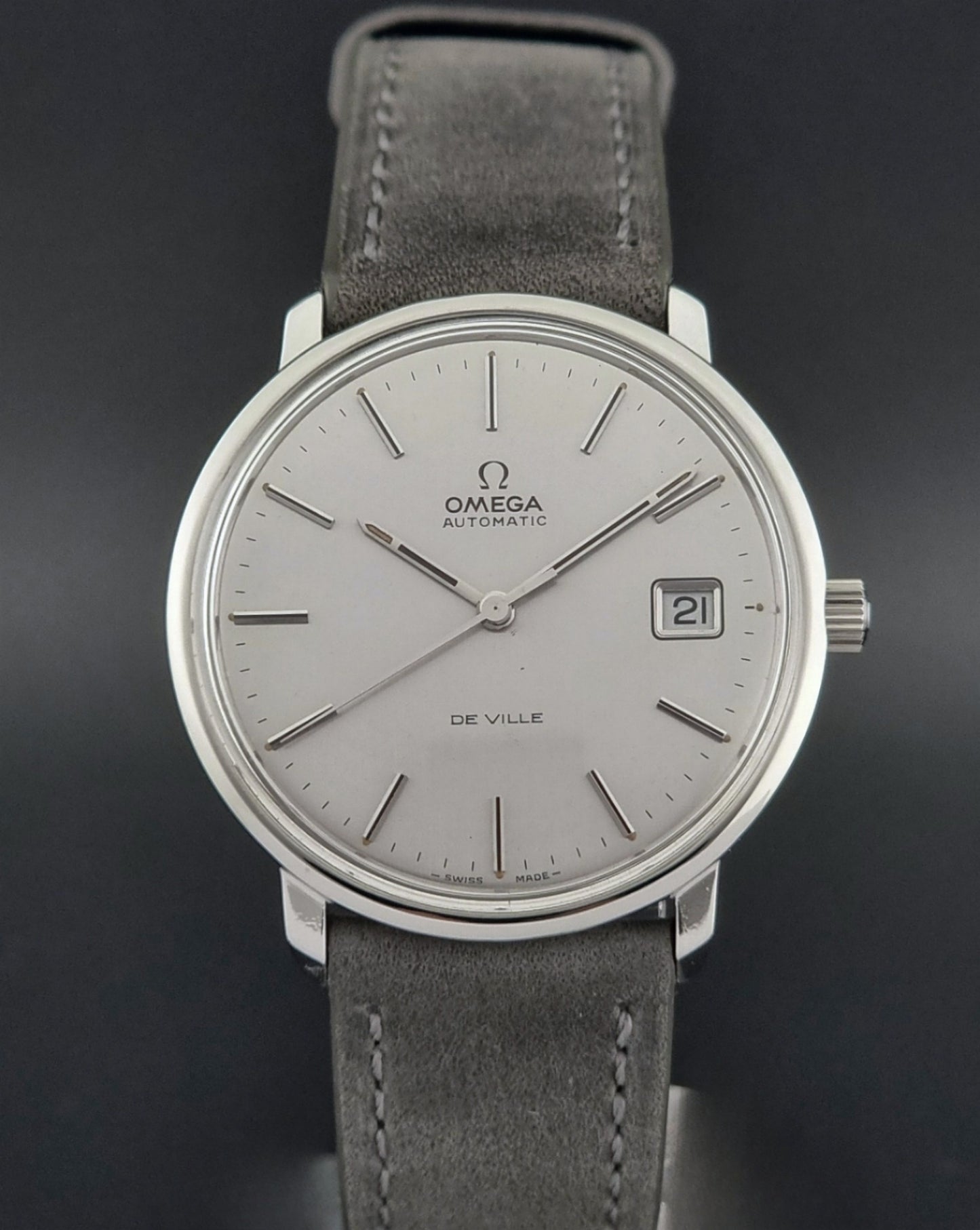 Vintage Omega De-ville 166.0134 wristwatch with a silver dial and dark leather strap on a gray background dial view