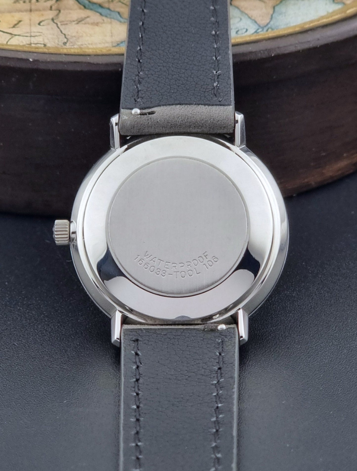 Vintage Omega Wristwatch De-Ville 166.033 with gray strap on a dark background case back