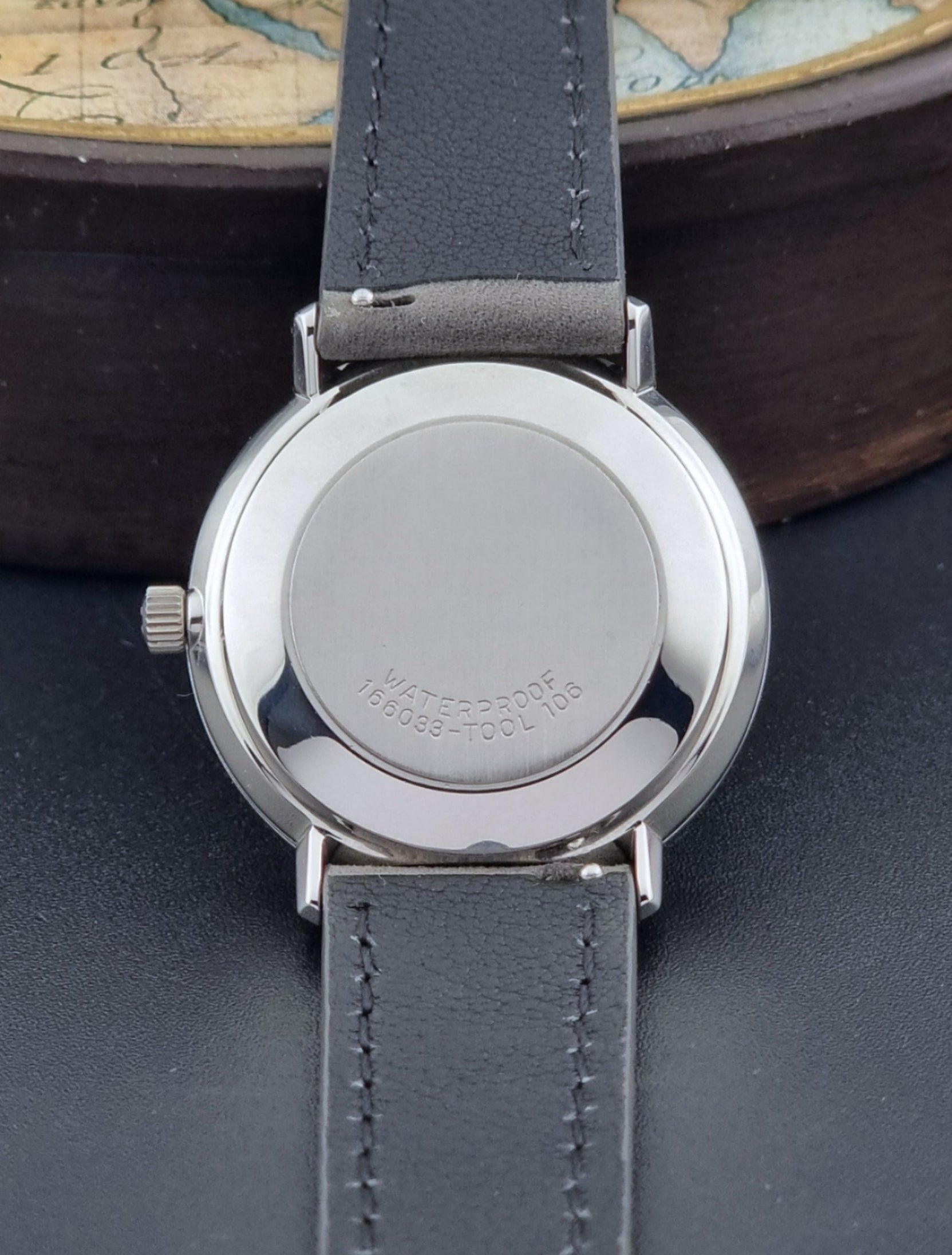 Vintage Omega Wristwatch De-Ville 166.033 with gray strap on a dark background case back