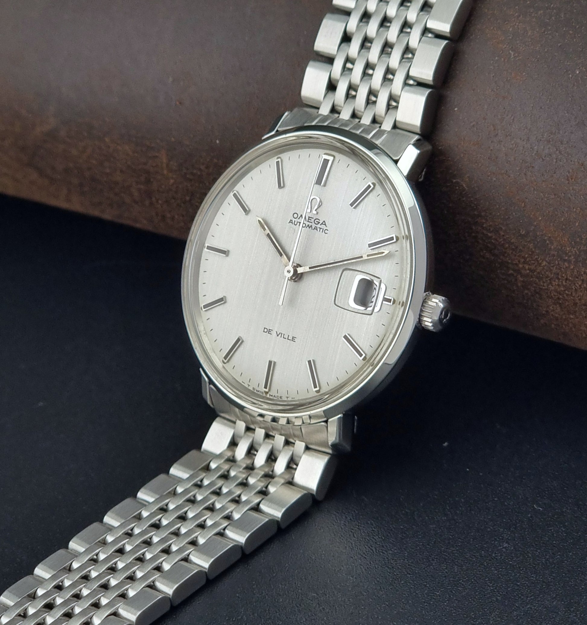 Vintage Omega De Ville watch with a white face on a dark surface