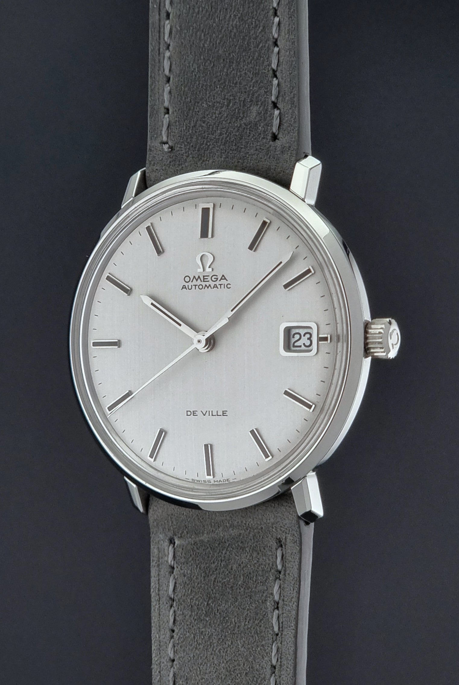 Vintage Omega Wristwatch De-Ville 166.033 with gray strap on a dark background crown side profile view