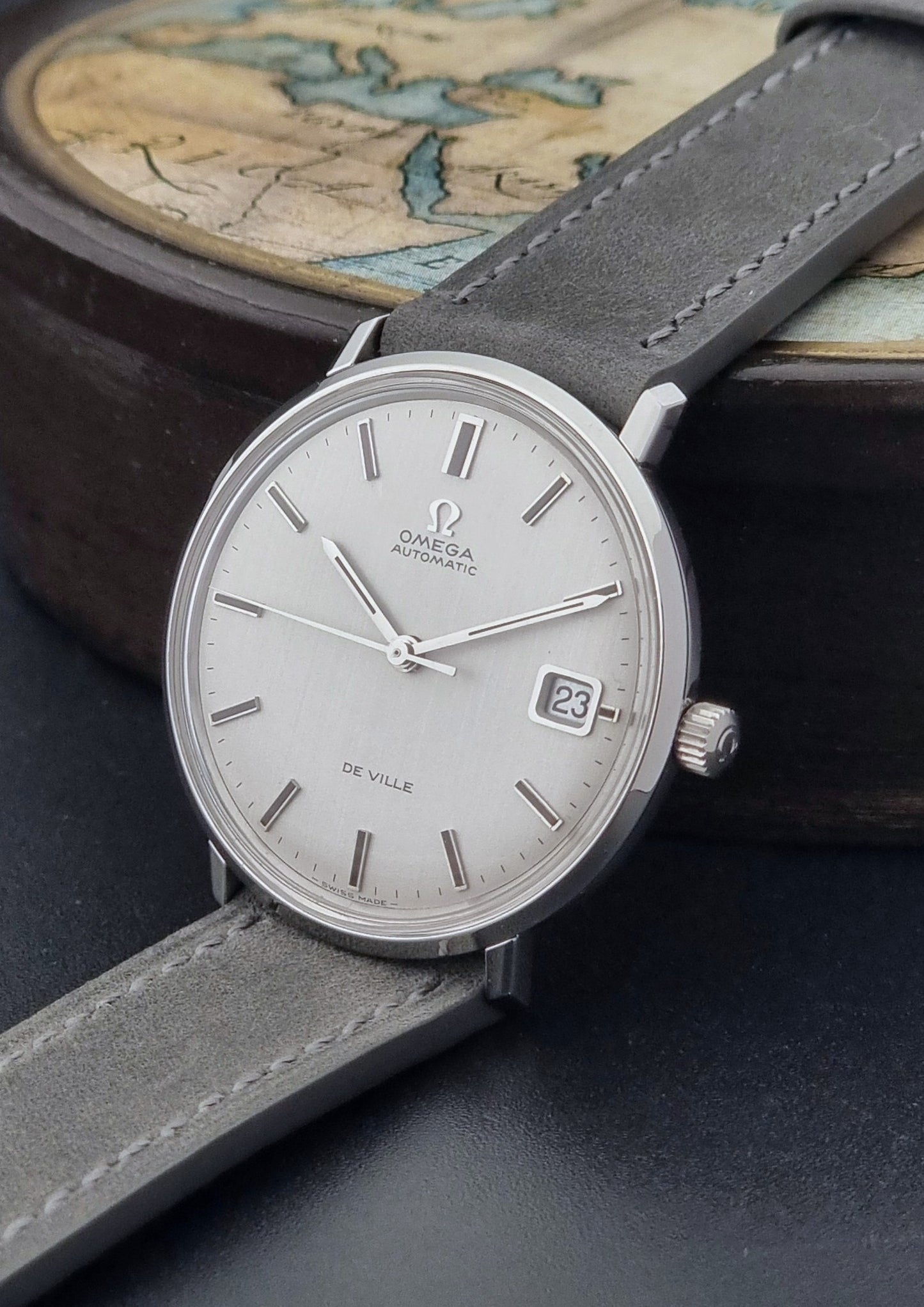 Vintage Omega Wristwatch De-Ville 166.033 with gray strap on a dark background crown view