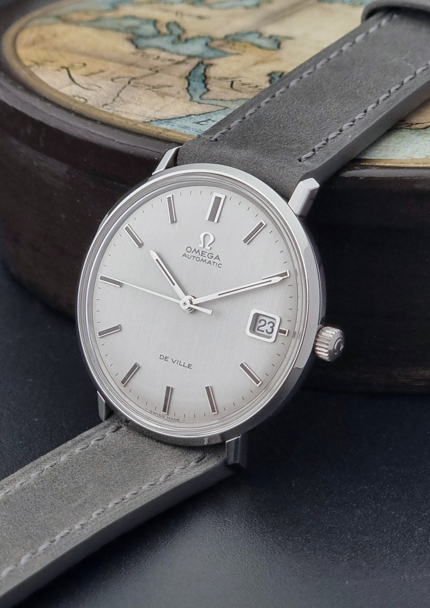 Vintage Omega Wristwatch De-Ville 166.033 with gray strap on a dark background crown view