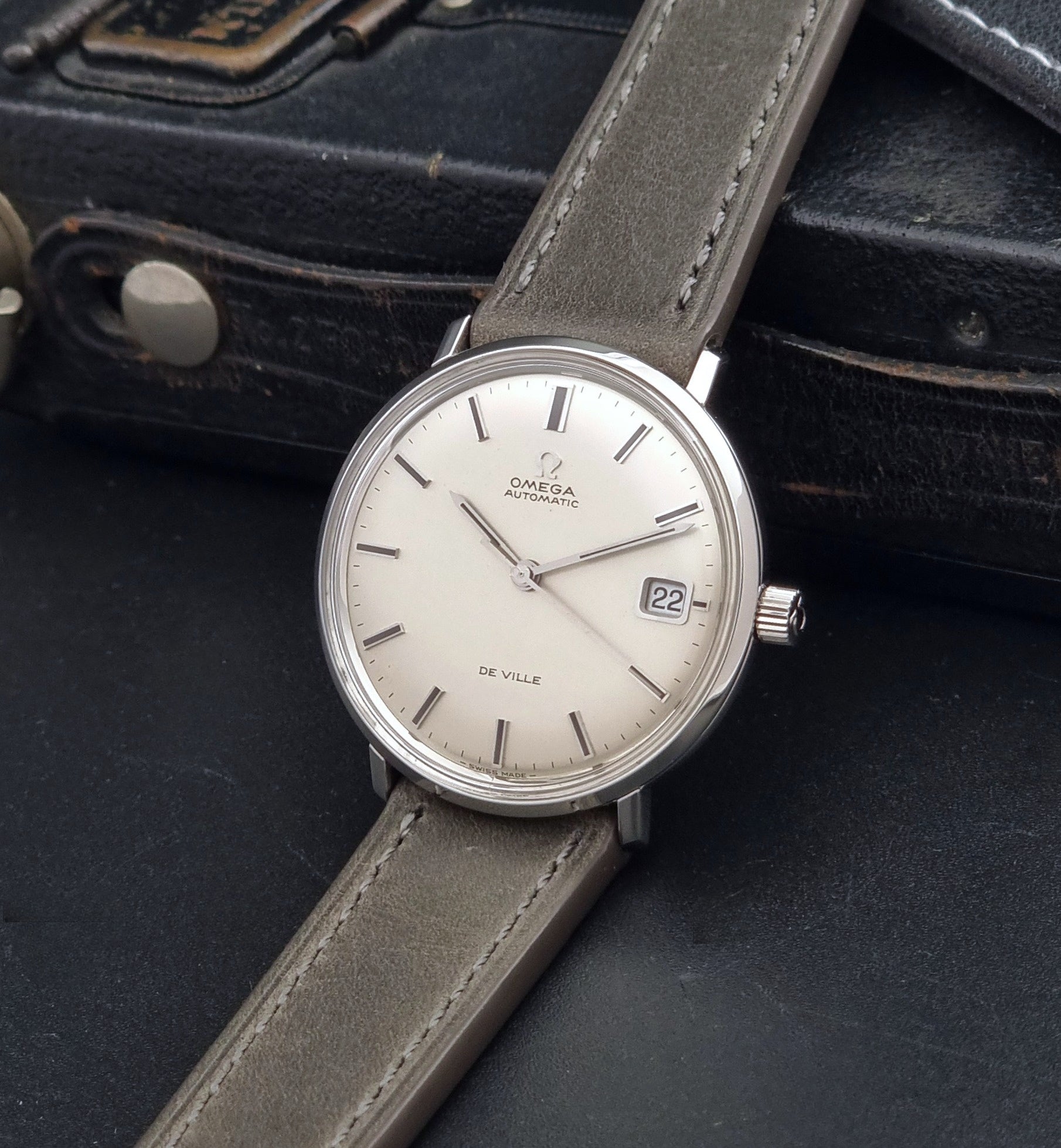 Vintage Omega De-Ville 166.033 Wristwatch with gray strap and white dial on a dark background crown view