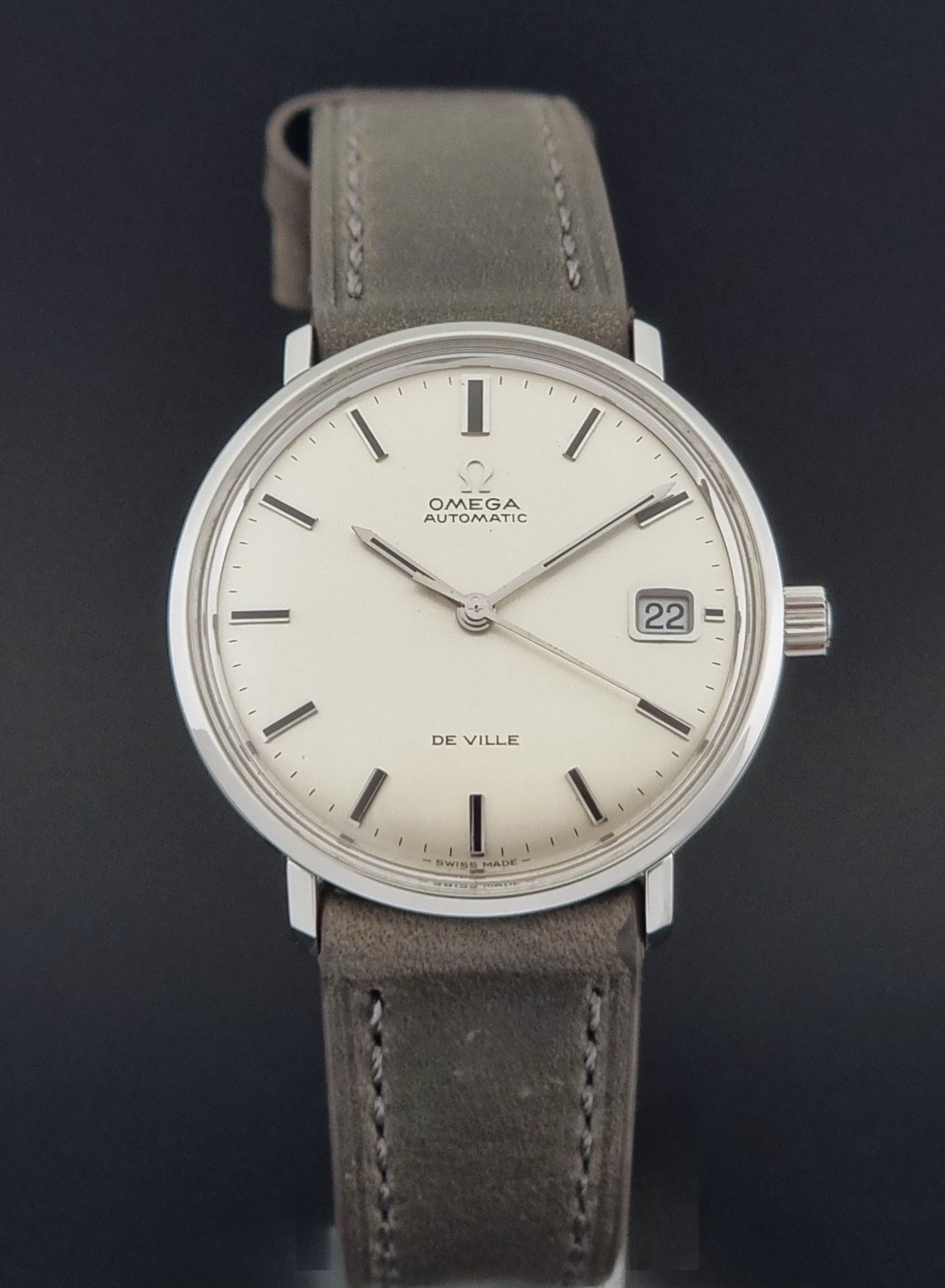Vintage Omega De-Ville 166.033 Wristwatch with gray strap and white dial on a dark background close dial view