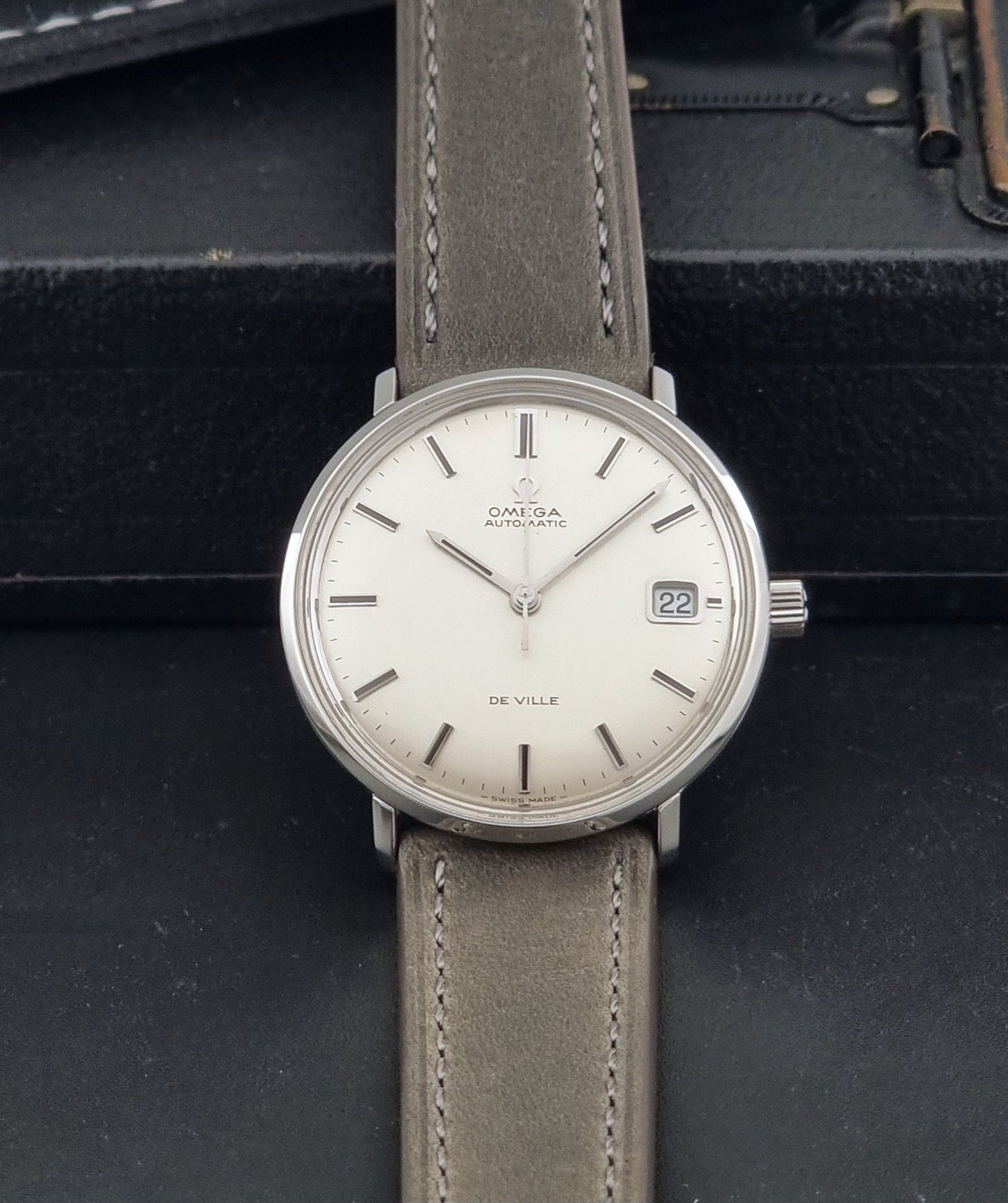 Vintage Omega De-Ville 166.033 Wristwatch with gray strap and white dial on a dark background dial view