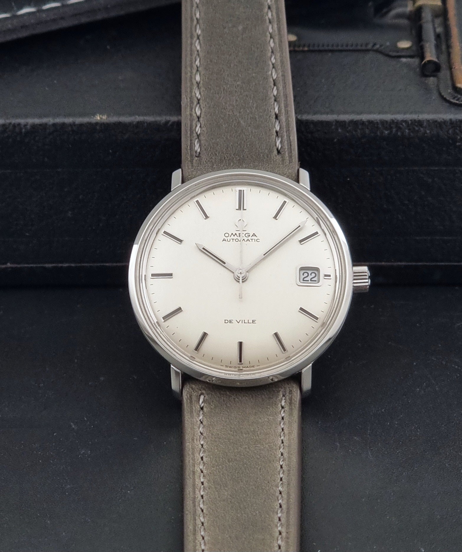 Vintage Omega De-Ville 166.033 Wristwatch with gray strap and white dial on a dark background dial view