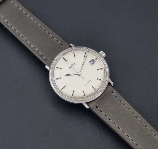 Vintage Omega De-Ville 166.033 Wristwatch with gray strap and white dial on a dark background dial