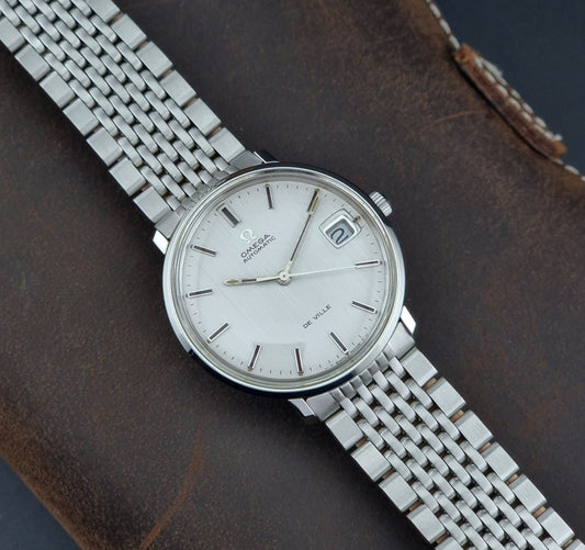 Vintage Omega De Ville watch on a brown leather background
