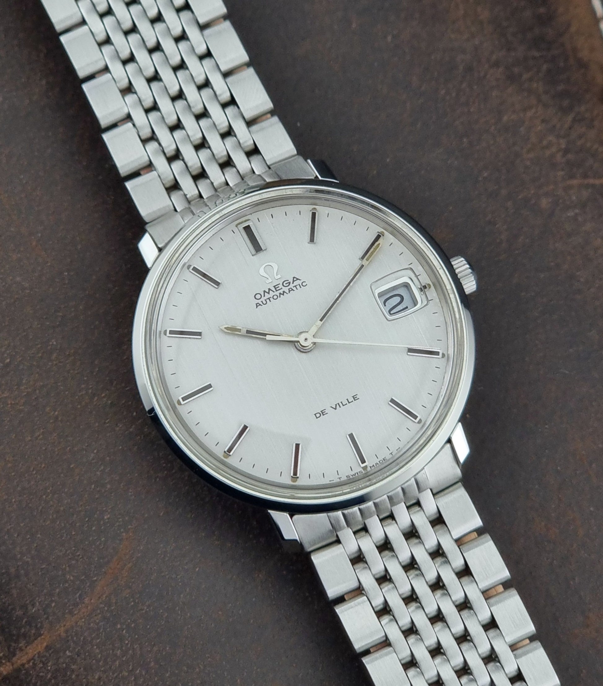 Vintage Omega De Ville watch on a dark brown leather background