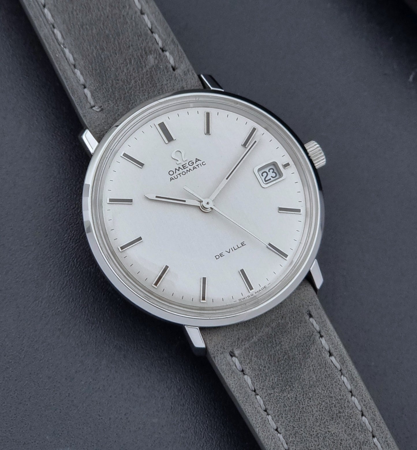 Vintage Omega Wristwatch De-Ville 166.033 with gray strap on a dark background close up