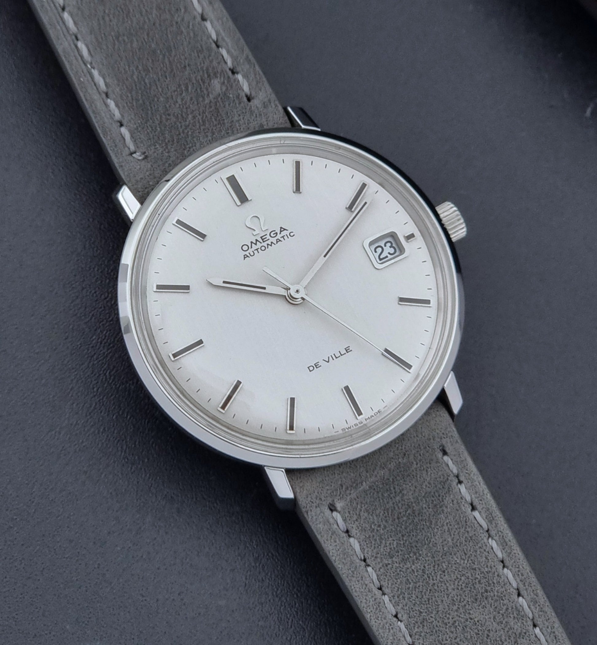 Vintage Omega Wristwatch De-Ville 166.033 with gray strap on a dark background close up