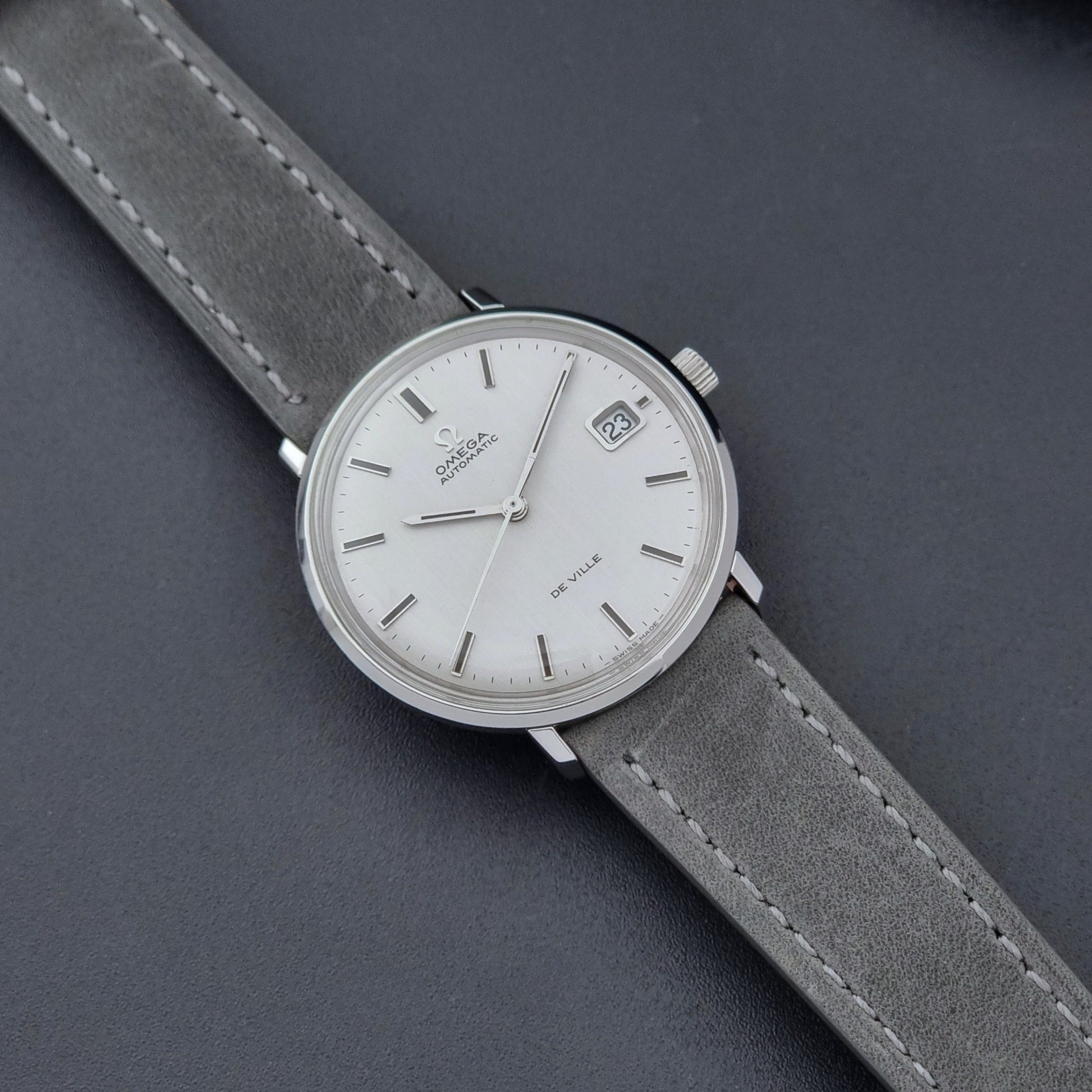 Vintage Omega Wristwatch De-Ville 166.033 with gray strap on a dark background