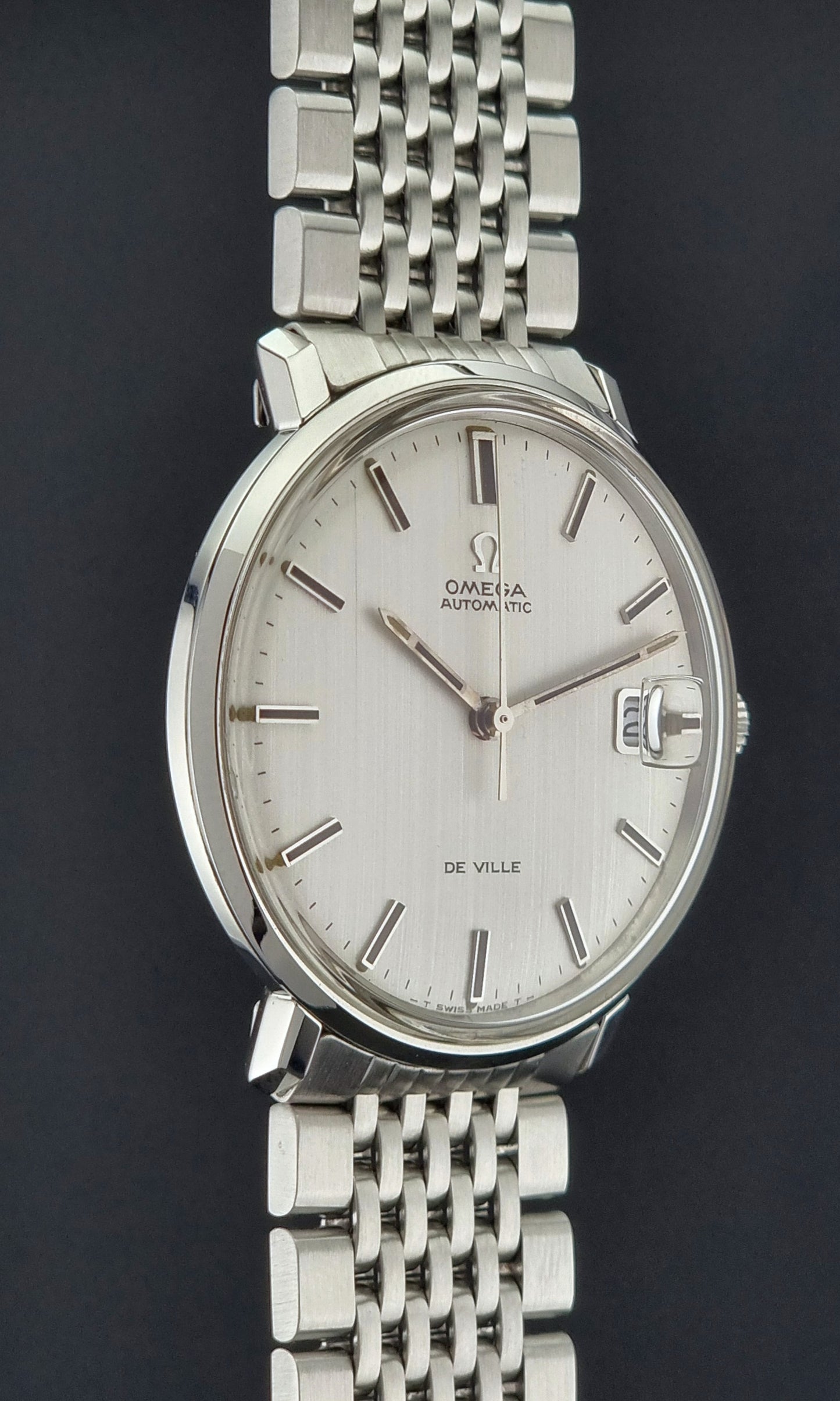 Vintage Omega De Ville watch with a white face on a dark background