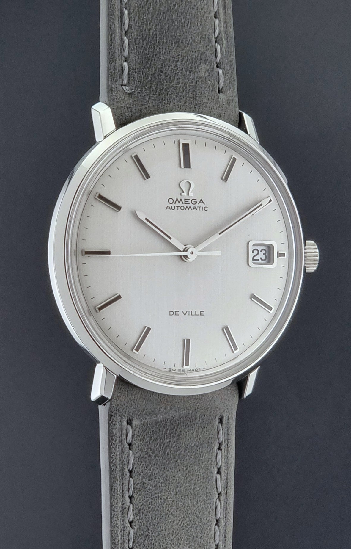 Vintage Omega Wristwatch De-Ville 166.033 with gray strap on a dark background side profile